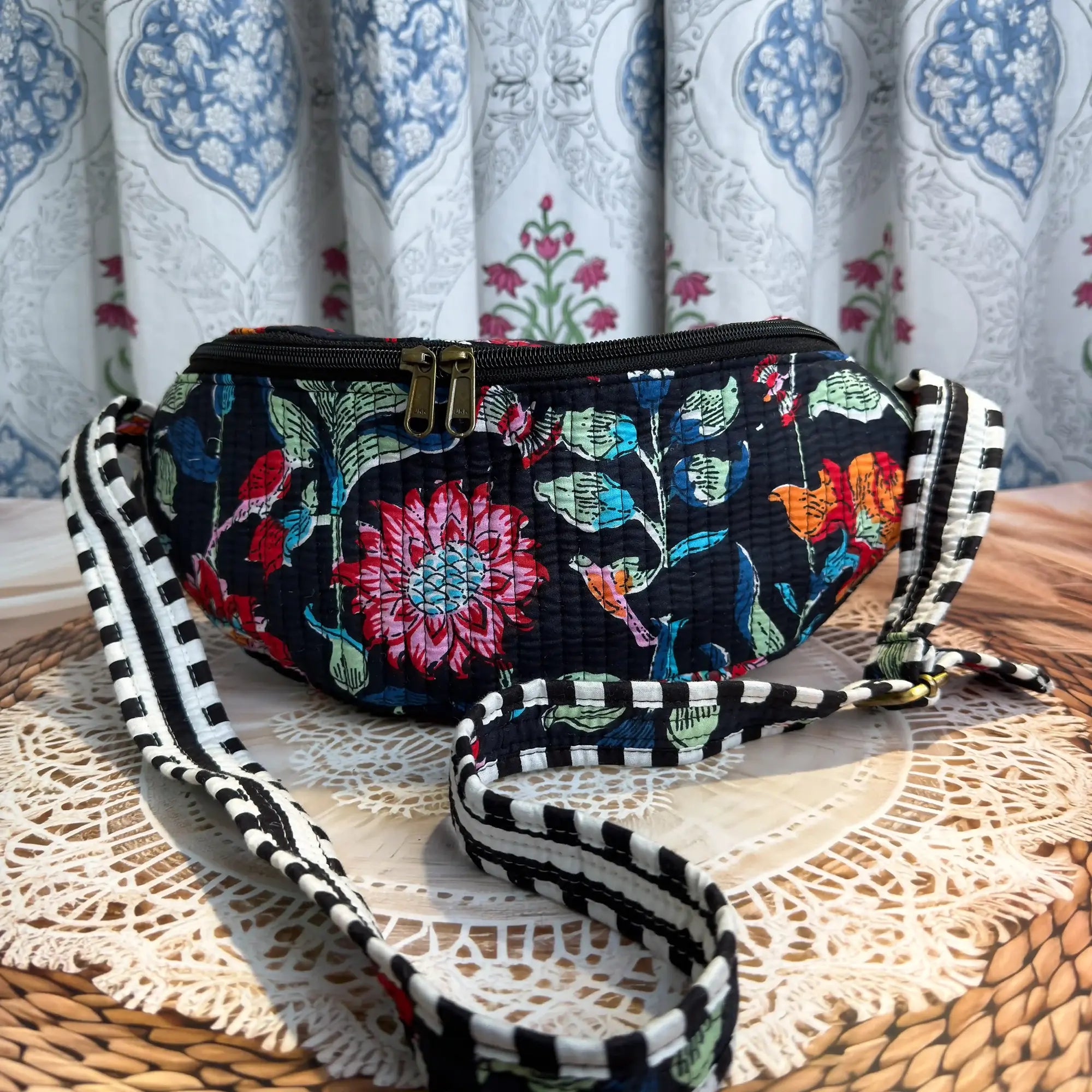 Black quilted cotton fanny bag with vibrant multicolor floral hand block print, adjustable waist strap for hands-free daily carry and travel