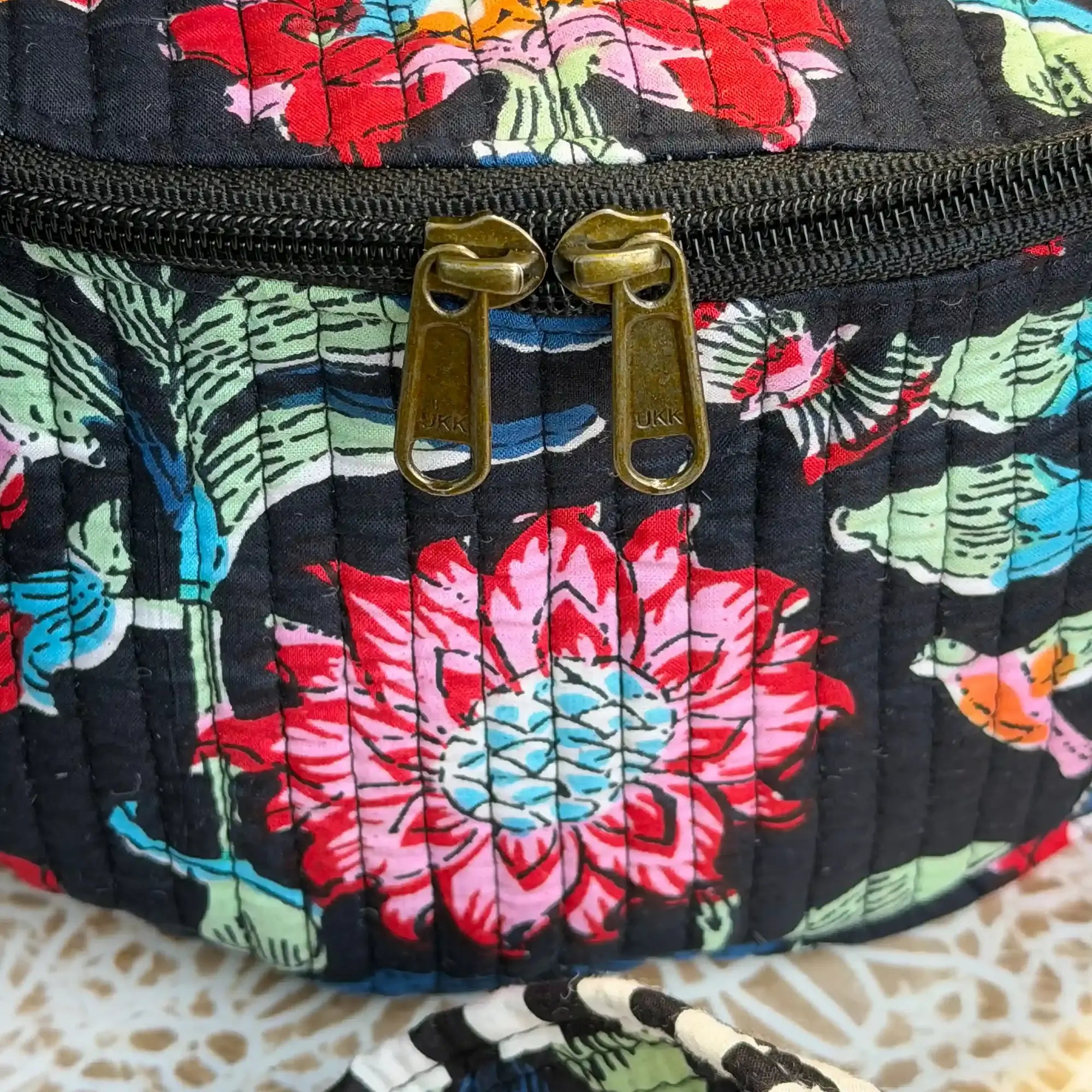 Black quilted cotton fanny bag with vibrant multicolor floral hand block print, adjustable waist strap for hands-free daily carry and travel