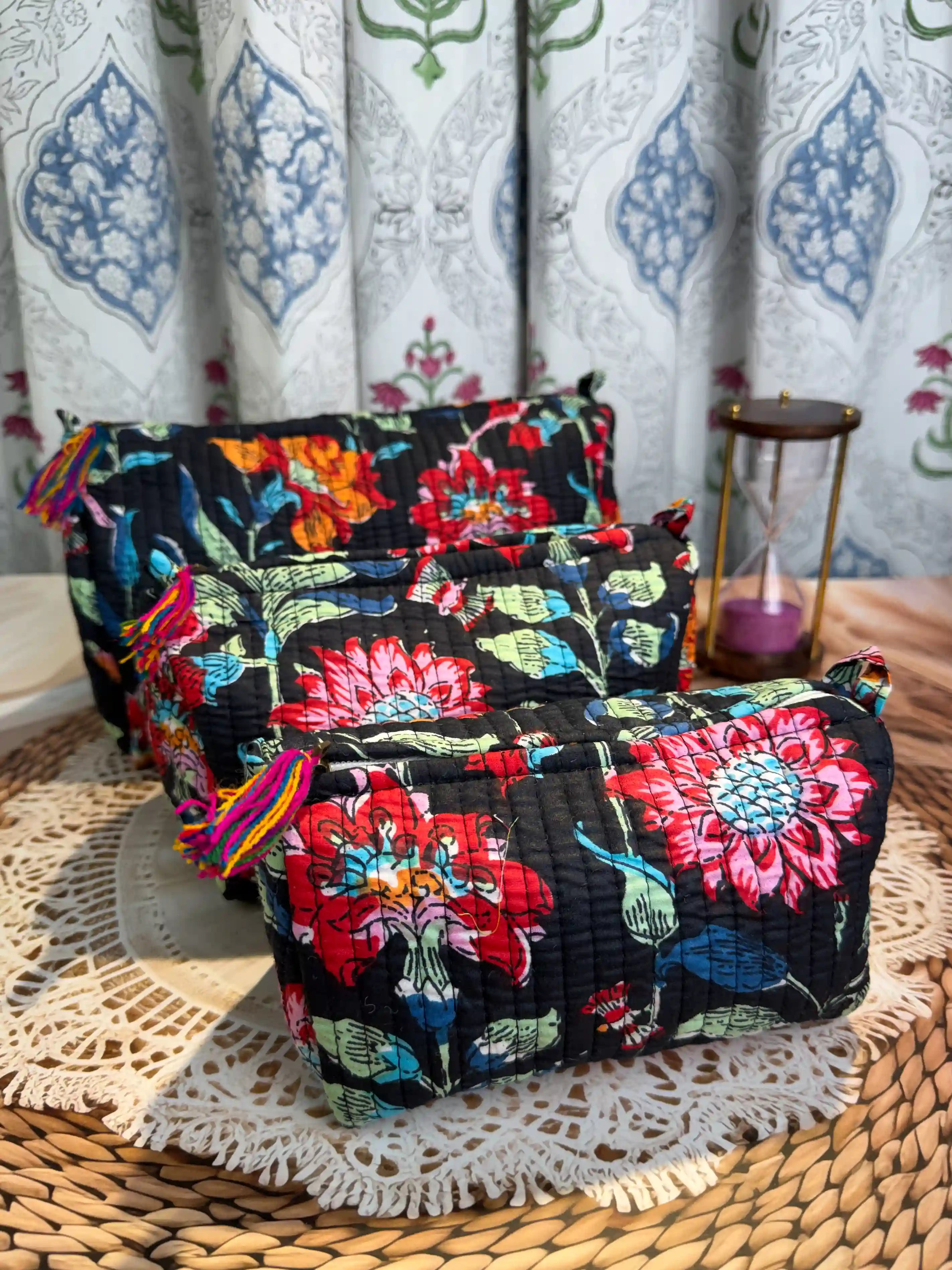Black quilted cotton toiletry pouch set with vibrant red and orange multicolor floral hand block print, three-piece handmade travel organizer.