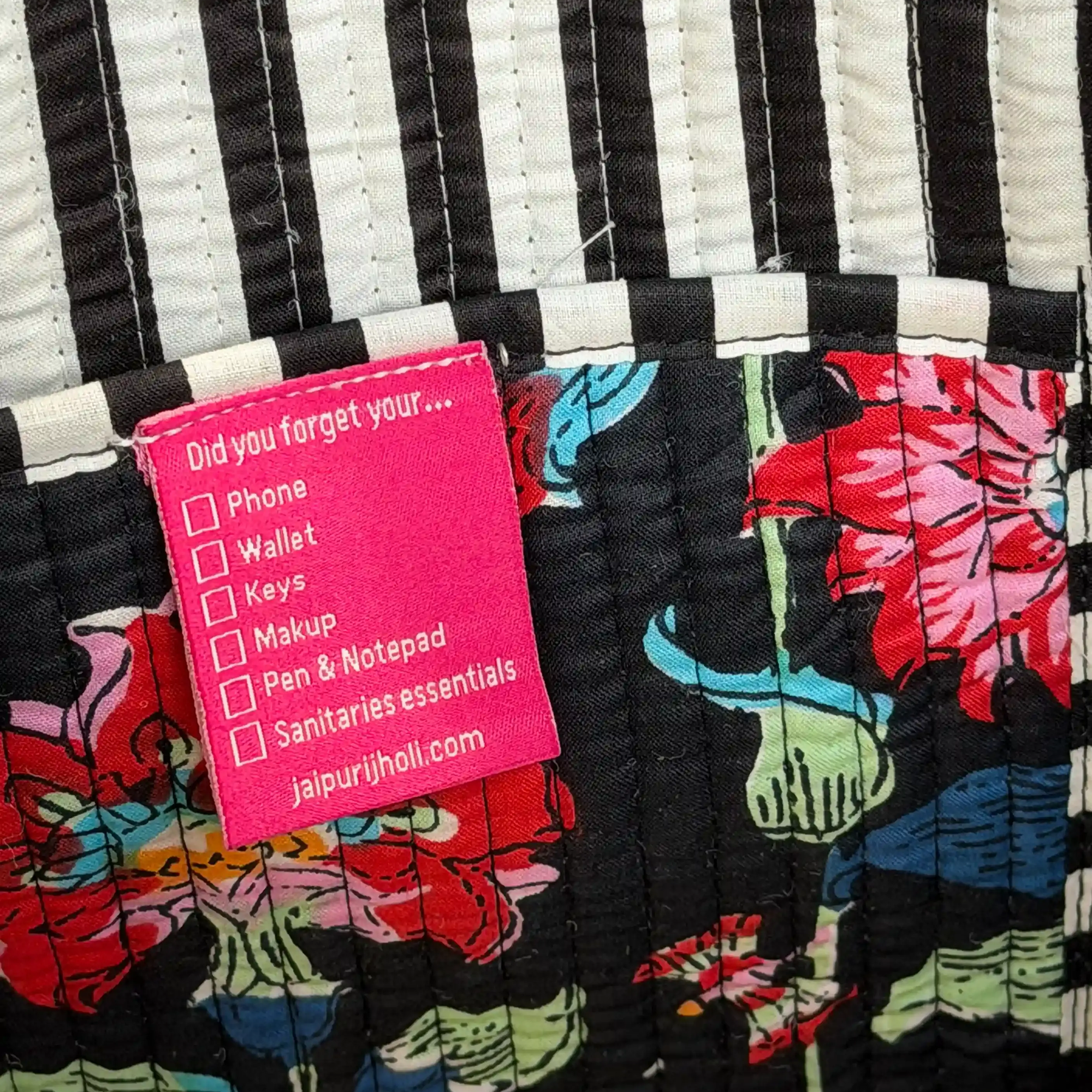 Black quilted cotton tote bag with multicolor floral hand block design, striped geometric borders, and zip closure, spacious everyday carryall.