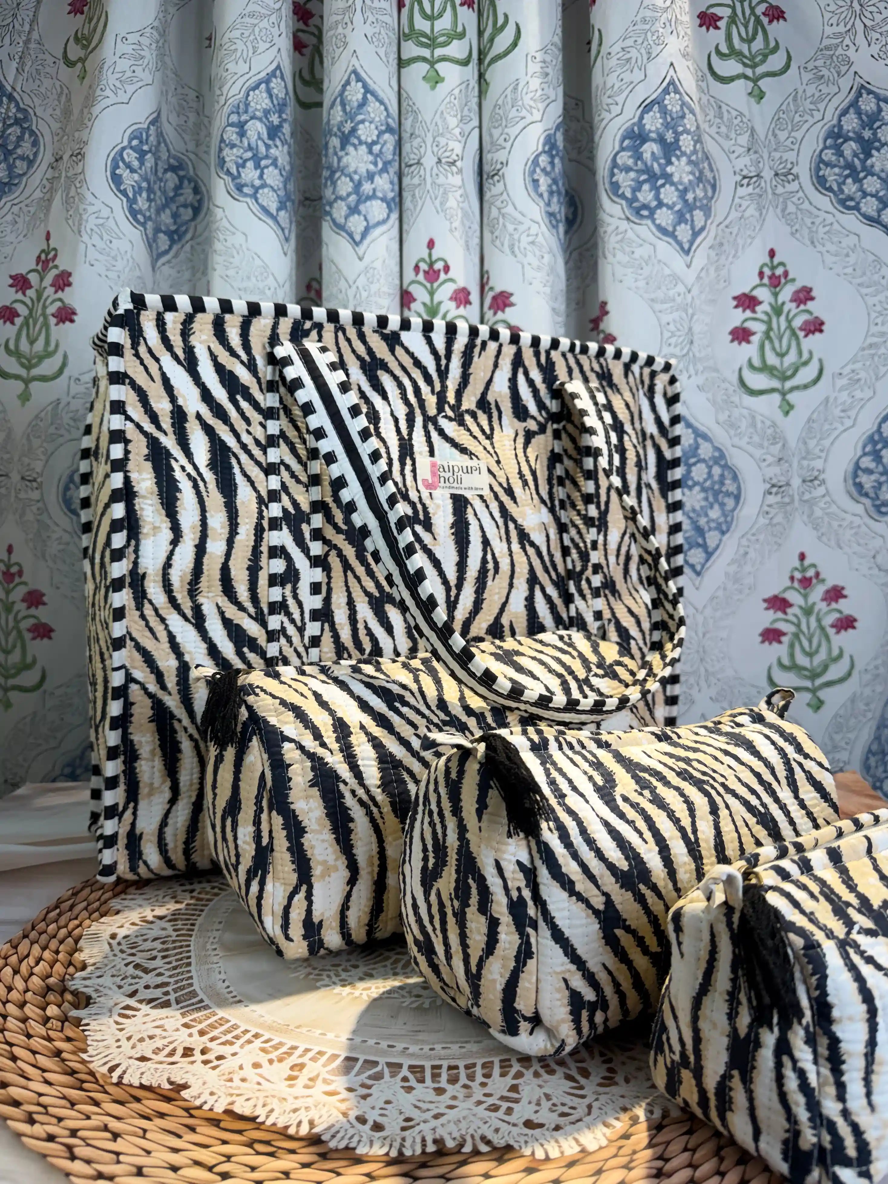 Handcrafted black and cream tiger print cotton quilted tote bag with sturdy striped handles and matching 3-piece zippered toiletry pouch set, featuring soft quilted texture, single compartments, and ethical craftsmanship from Jaipur, India, ideal for everyday use, travel, cosmetics, skincare, and innerwear storage