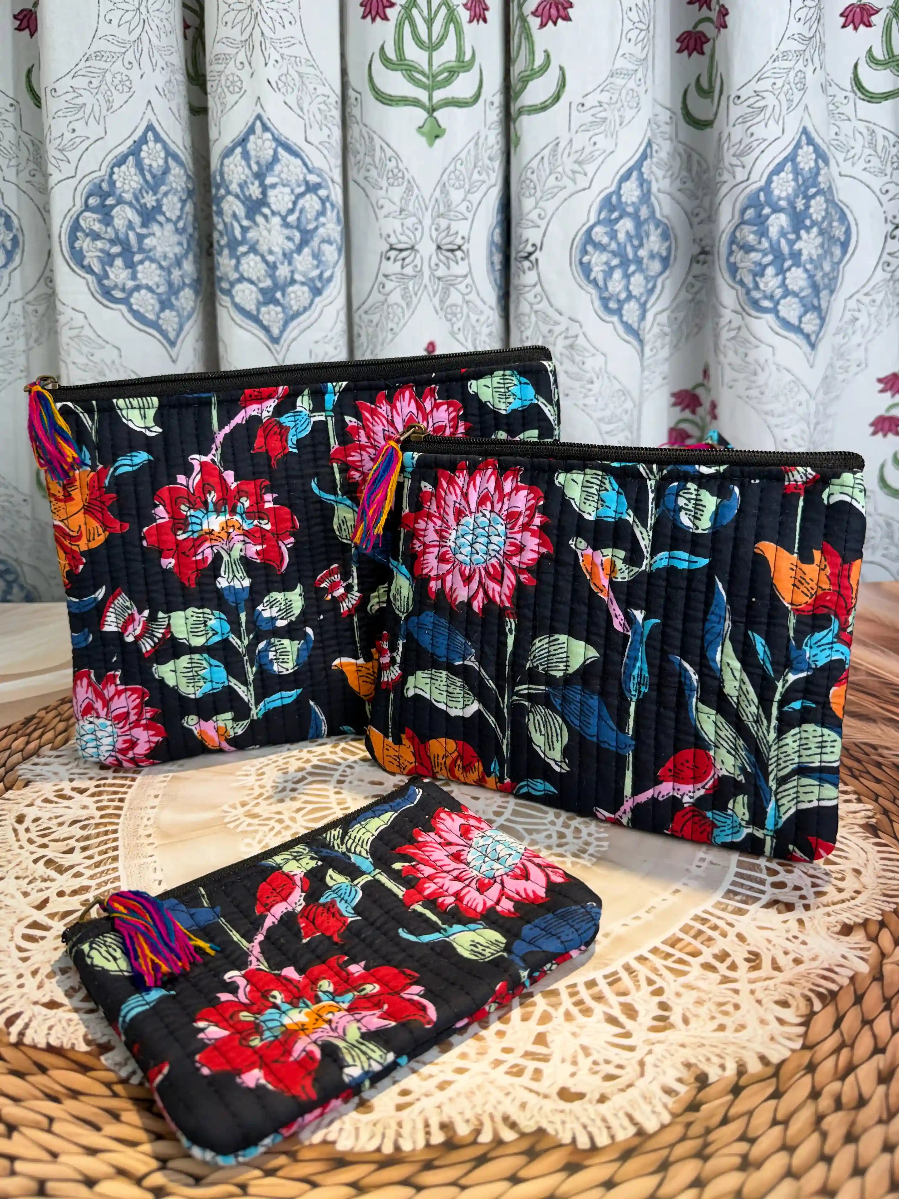 Black quilted cotton flat pouch set with red and orange multicolor floral hand block print, three-piece handcrafted zipper pouches for organization.