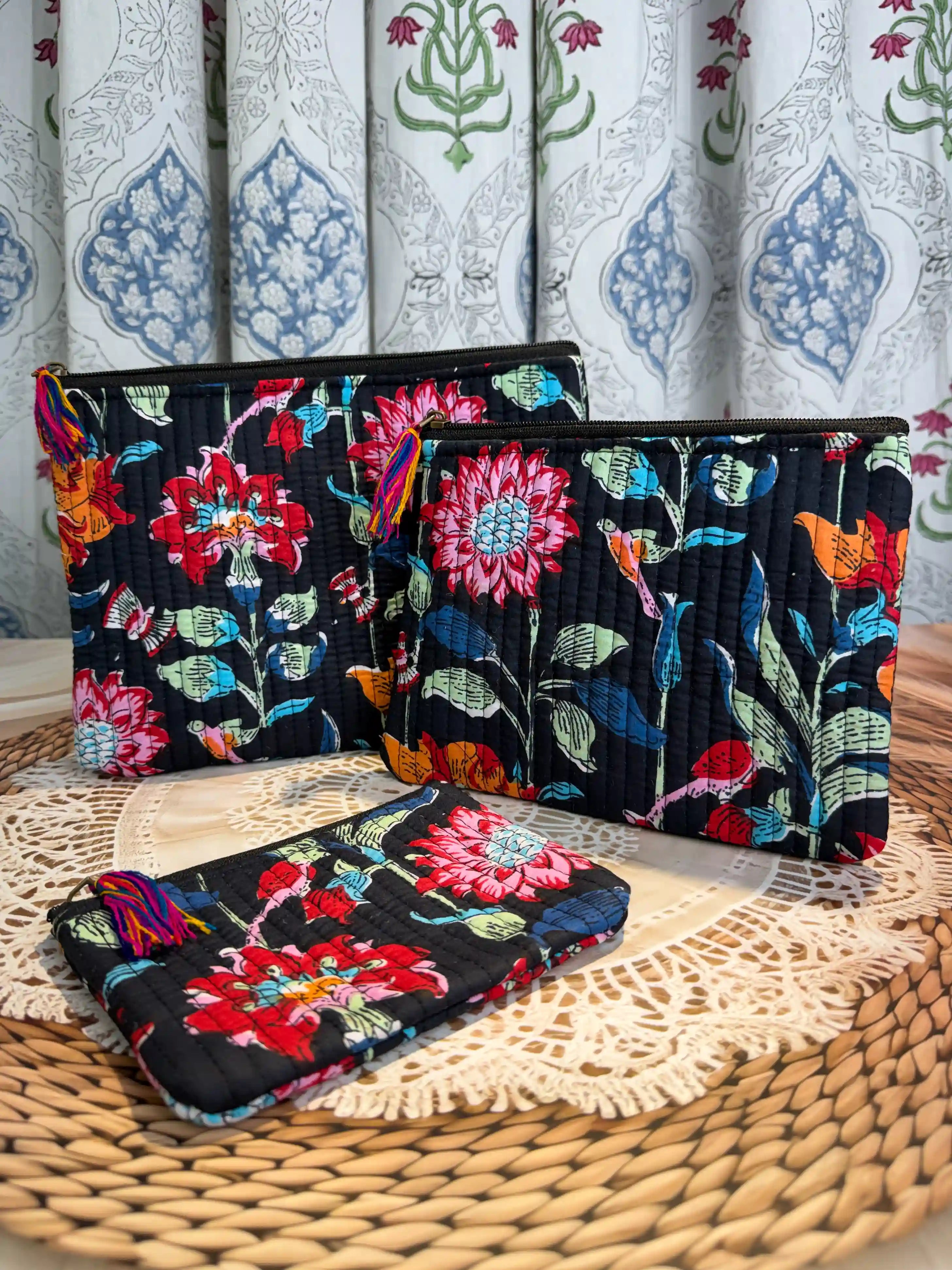 Black quilted cotton flat pouch set with red and orange multicolor floral hand block print, three-piece handcrafted zipper pouches for organization.