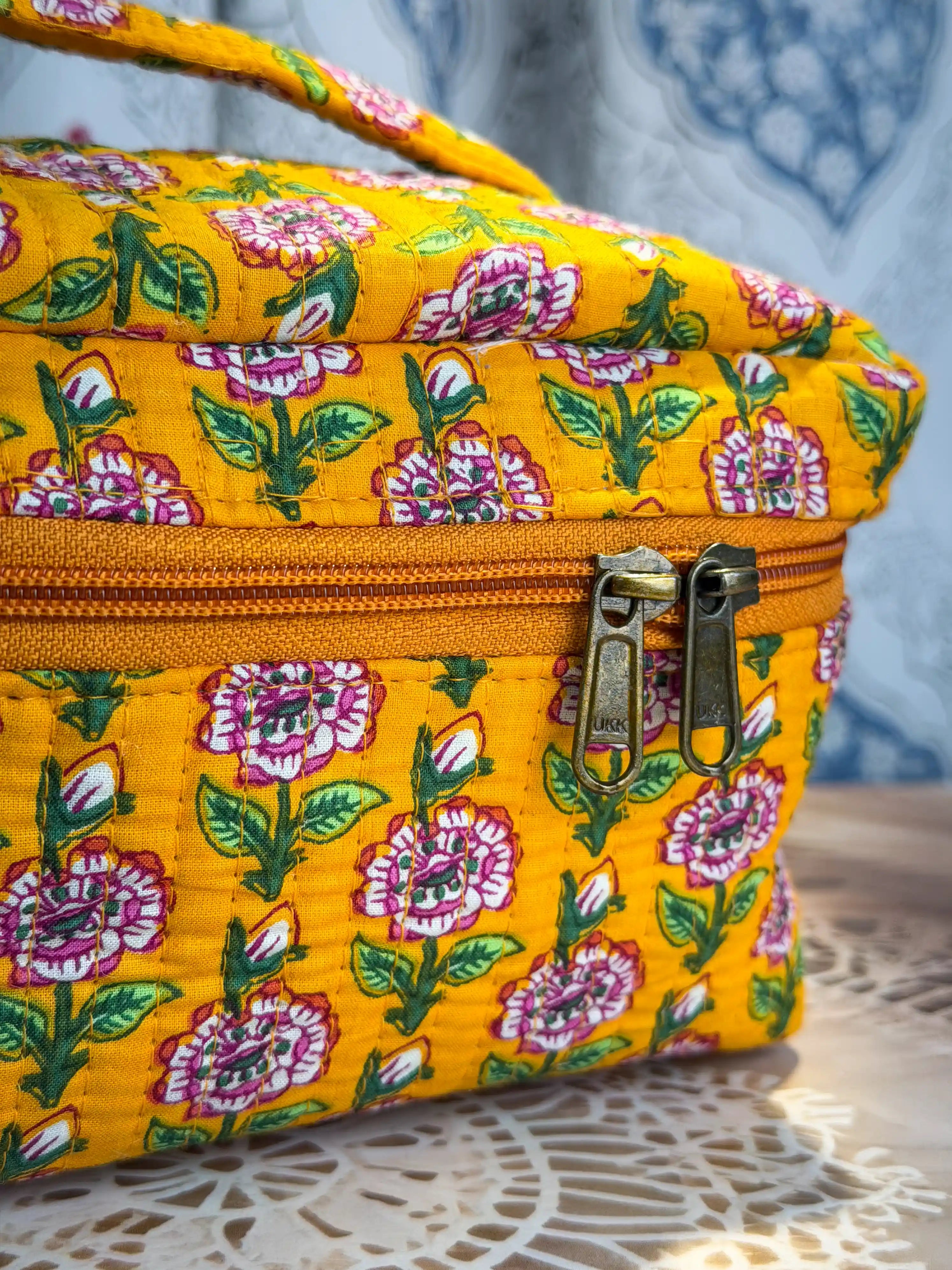 Bright yellow quilted cotton cosmetic vanity bag with purple and green multicolor floral hand block design, cheerful handcrafted makeup organizer for daily use