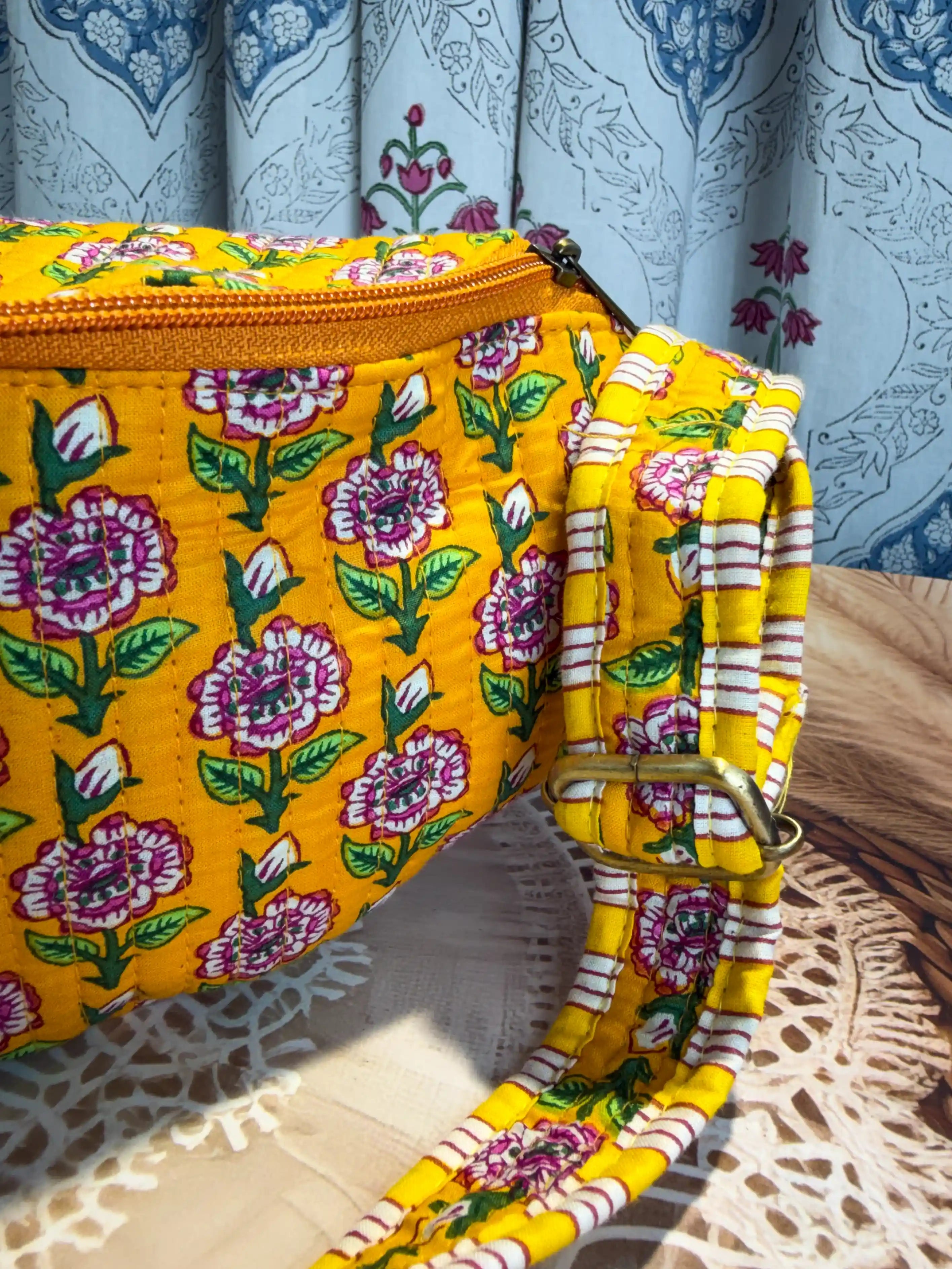 Bright yellow quilted cotton fanny bag with purple and green multicolor floral hand block print, striped waist strap for daily and travel use 