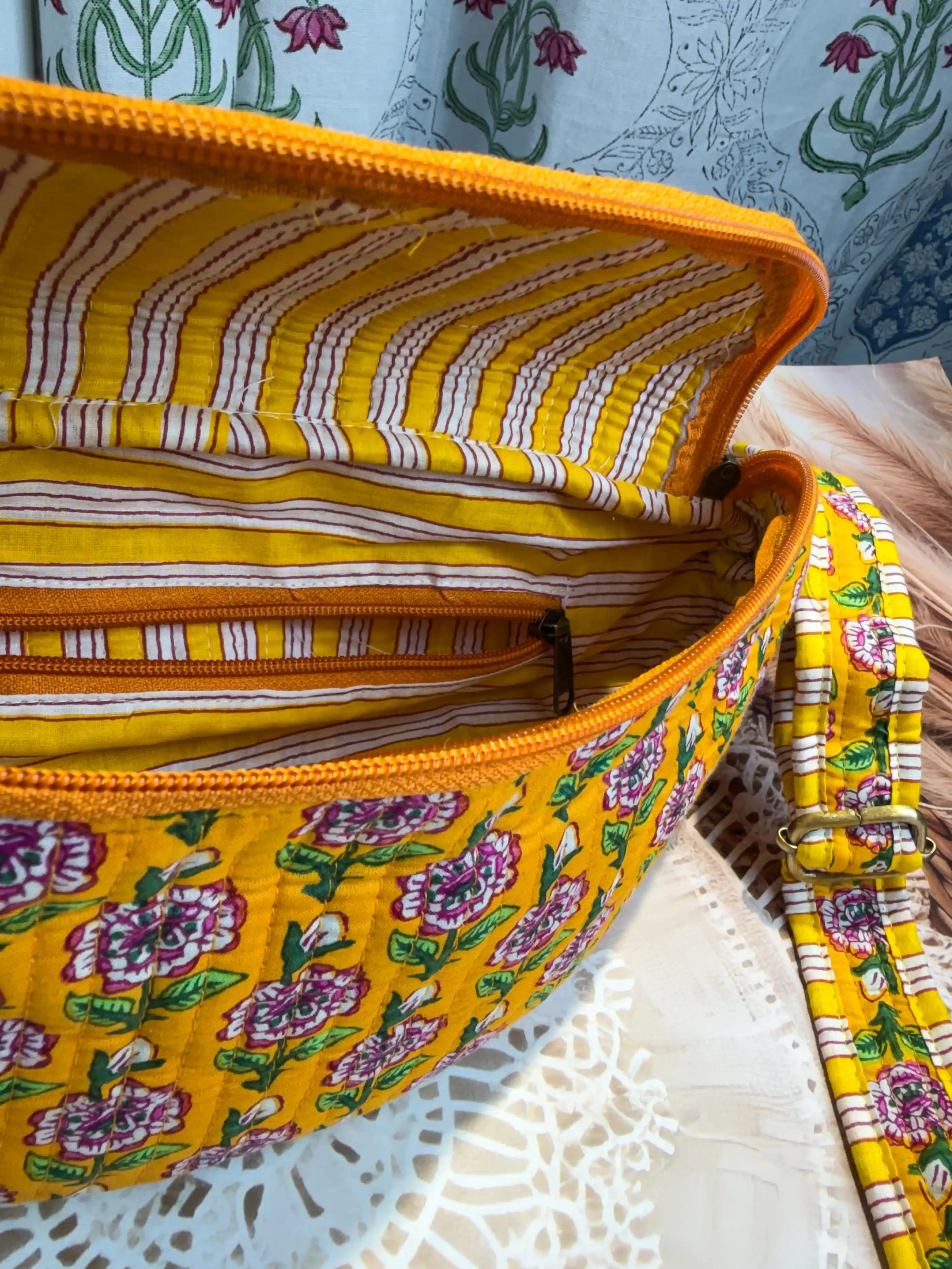 Bright yellow quilted cotton fanny bag with purple and green multicolor floral hand block print, striped waist strap for daily and travel use