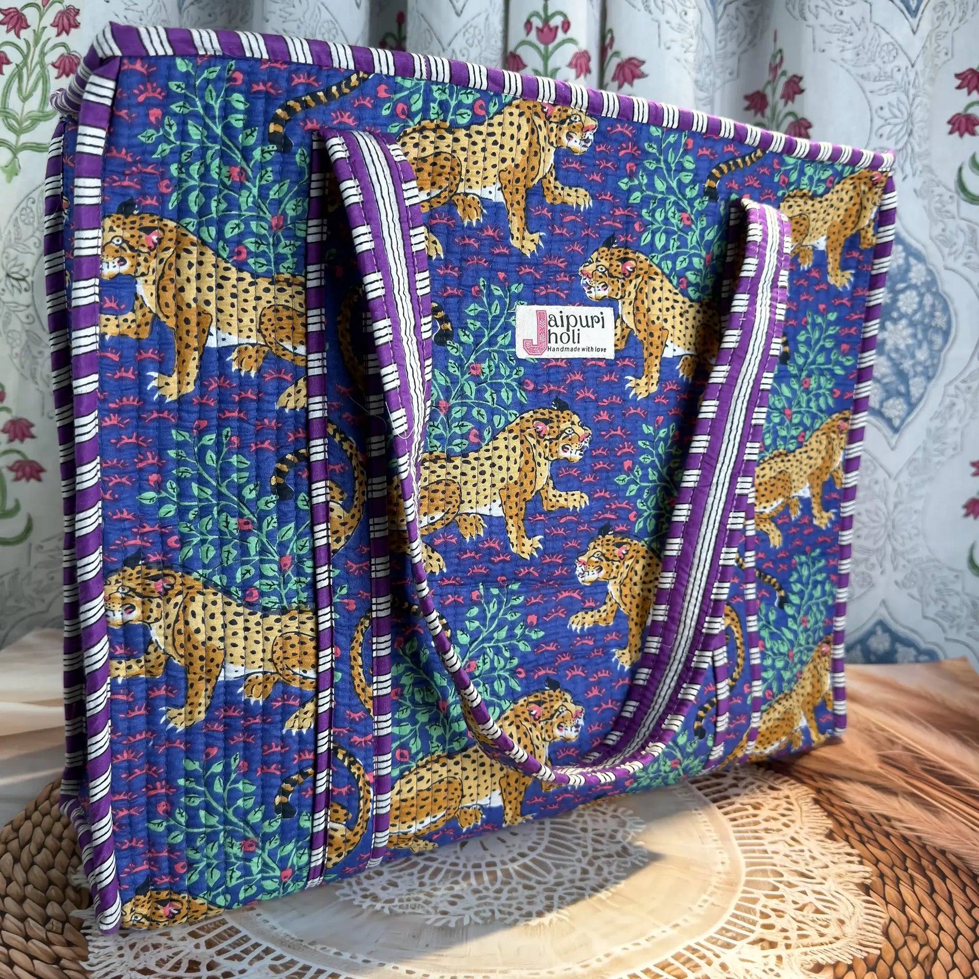 Deep blue quilted cotton tote bag with yellow animal print hand block design, green leaf accents, and zip, bold statement shoulder bag for travel.