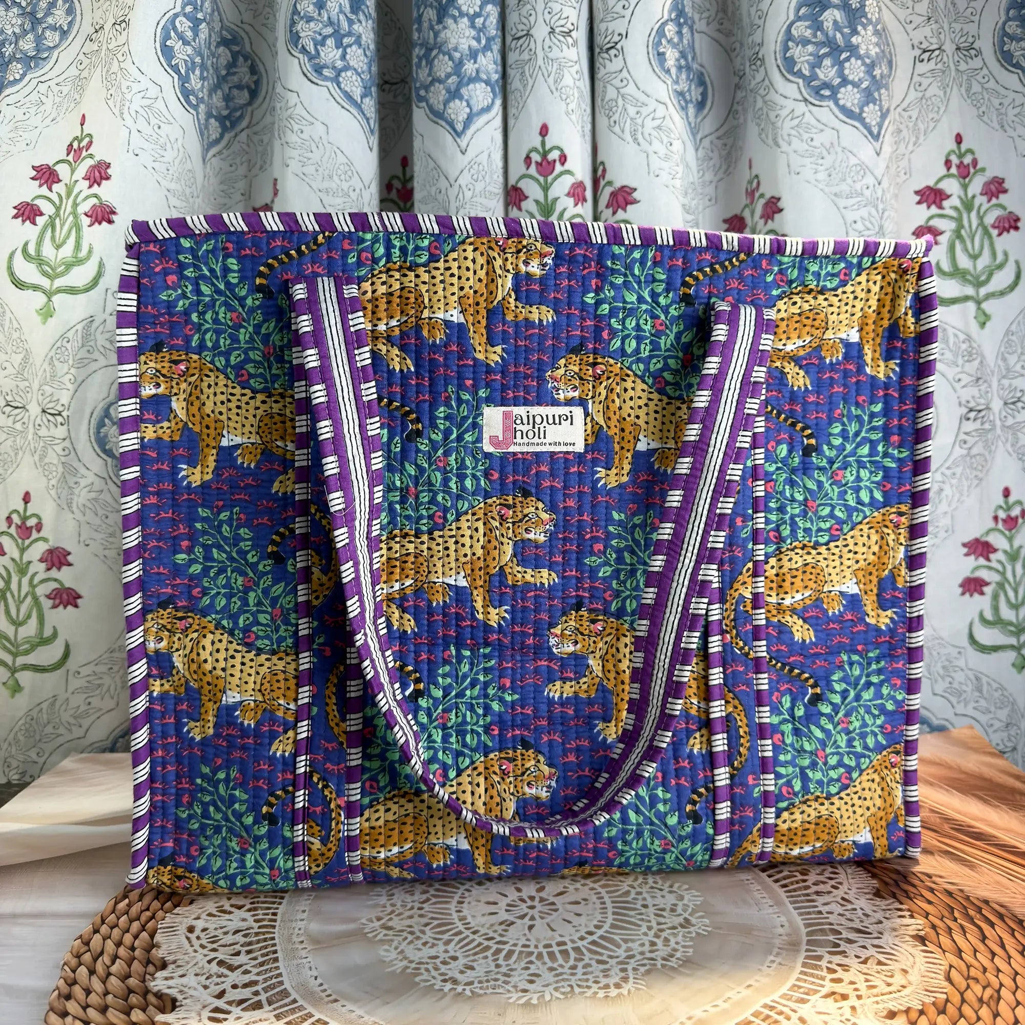 Deep blue quilted cotton tote bag with yellow animal print hand block design, green leaf accents, and zip, bold statement shoulder bag for travel.