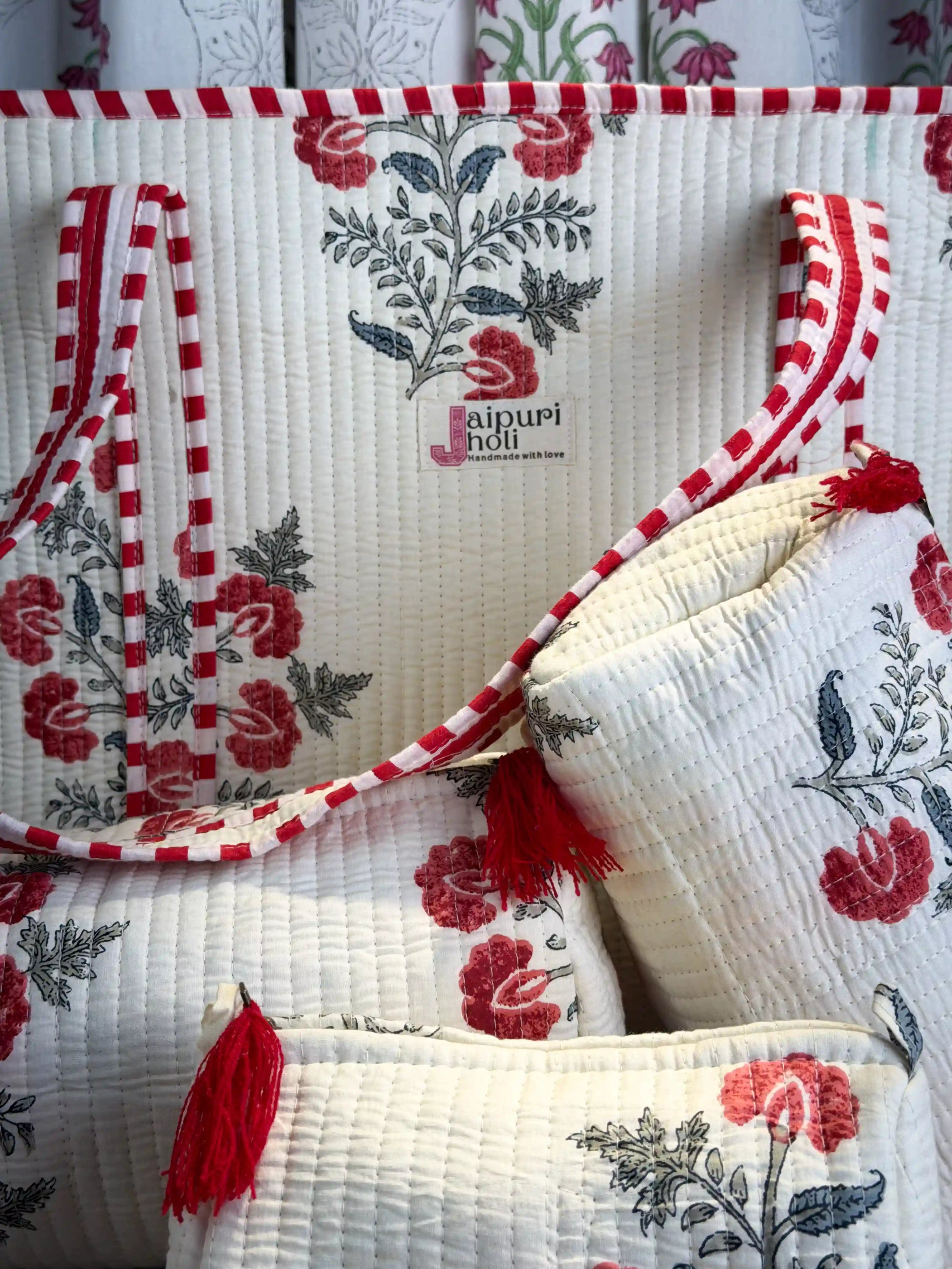Handcrafted white cotton quilted tote bag with red floral block print and striped handles, paired with a matching 3-piece zippered toiletry pouch set, featuring soft quilted texture, single compartments, and ethical craftsmanship from Jaipur, India, ideal for everyday use, travel, cosmetics, skincare, and innerwear storage