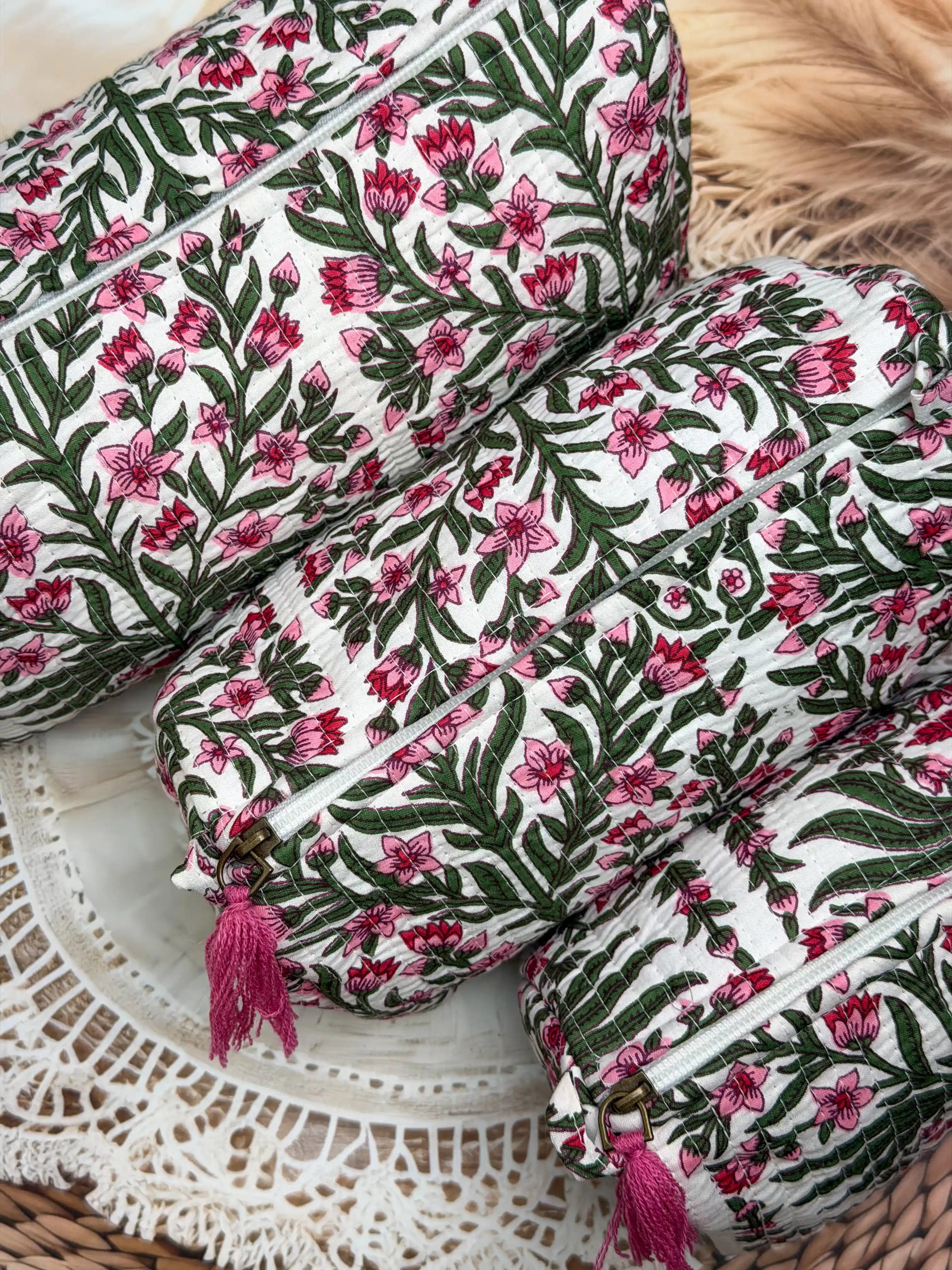 White quilted cotton toiletry pouch set with pink and green botanical floral hand block design, three-piece handcrafted organizer with pink tassels for daily use.