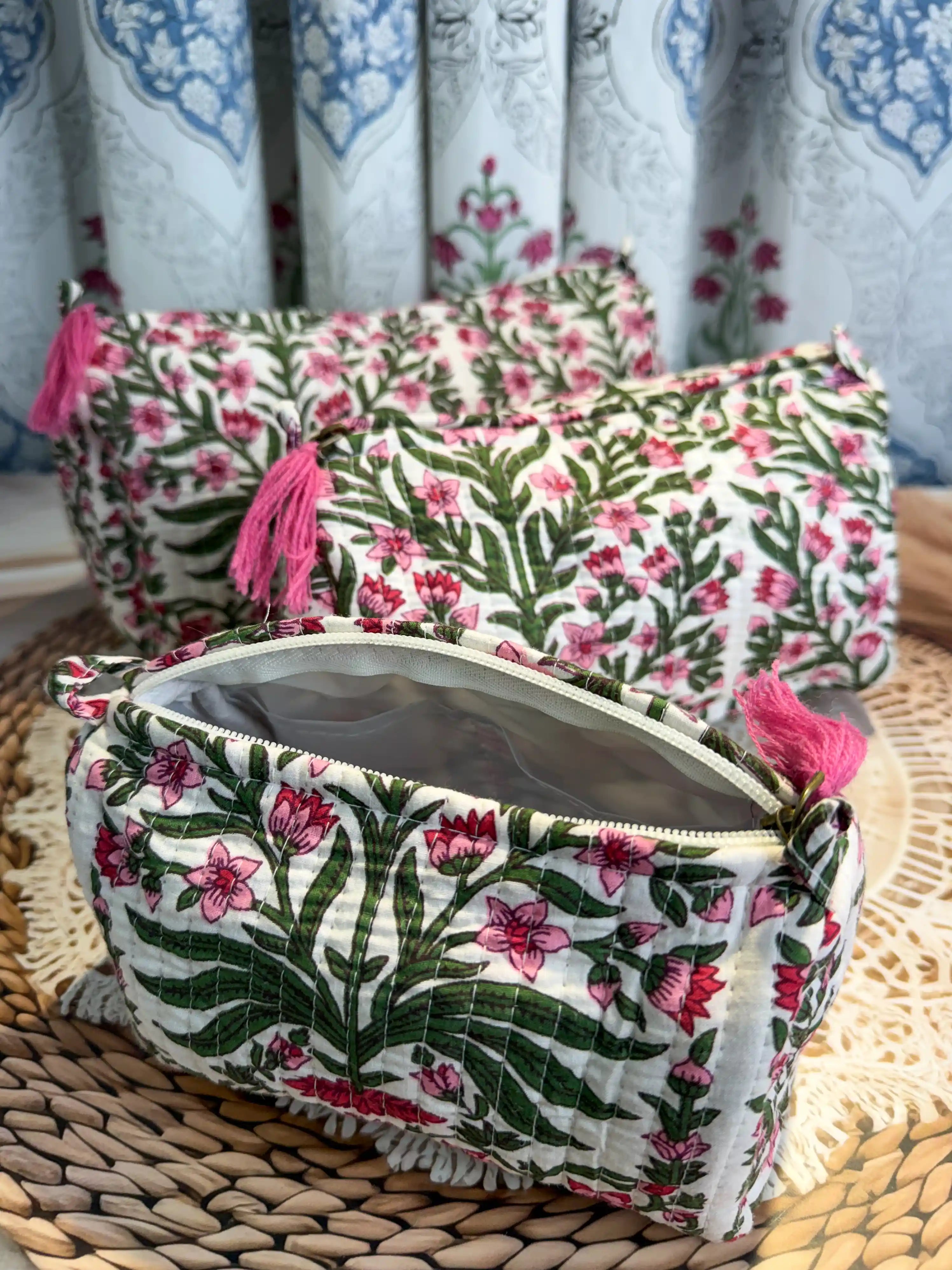White quilted cotton toiletry pouch set with pink and green botanical floral hand block design, three-piece handcrafted organizer with pink tassels for daily use.