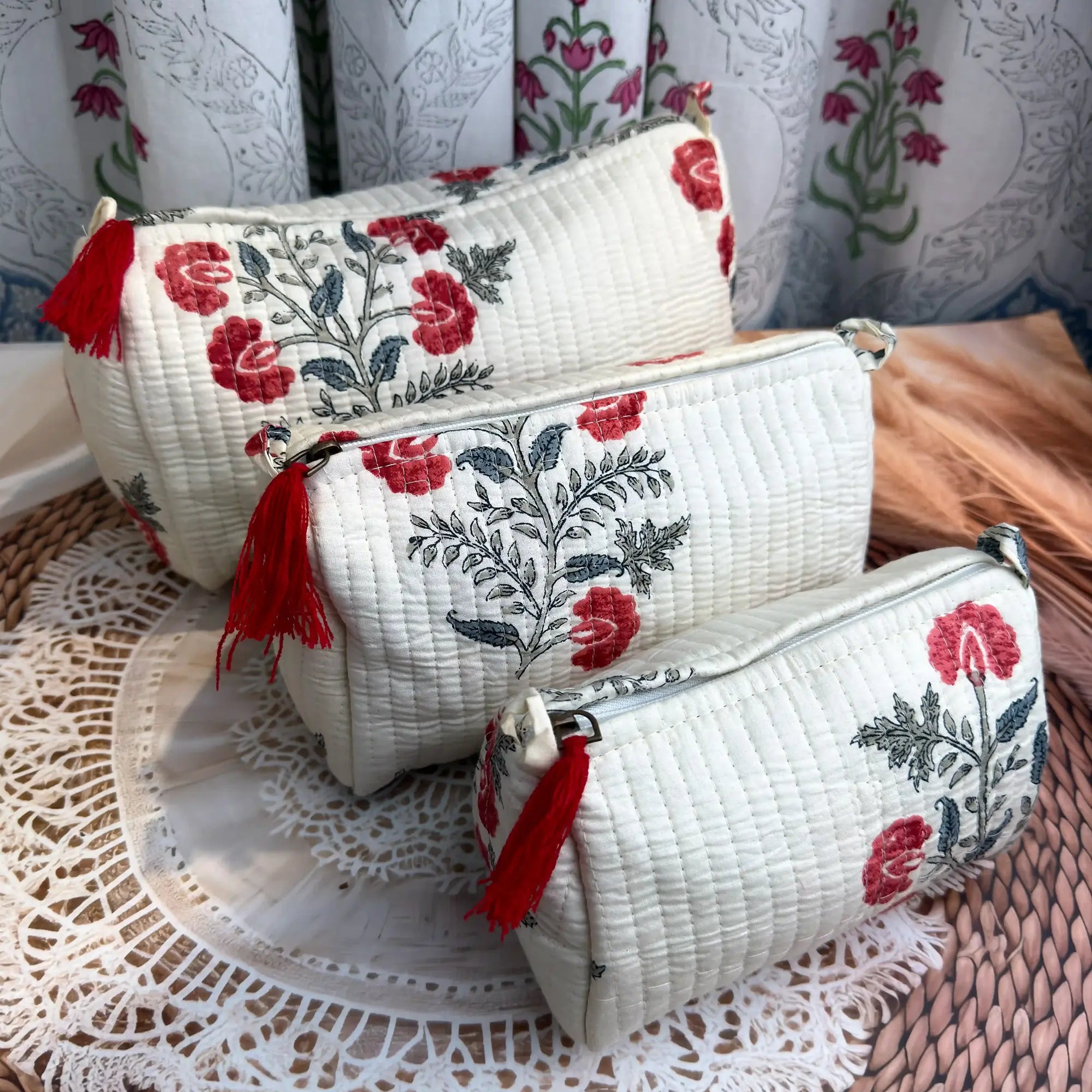 White quilted cotton toiletry pouch set with red and green botanical floral hand block print, three-piece handcrafted organizer with tassels for travel.