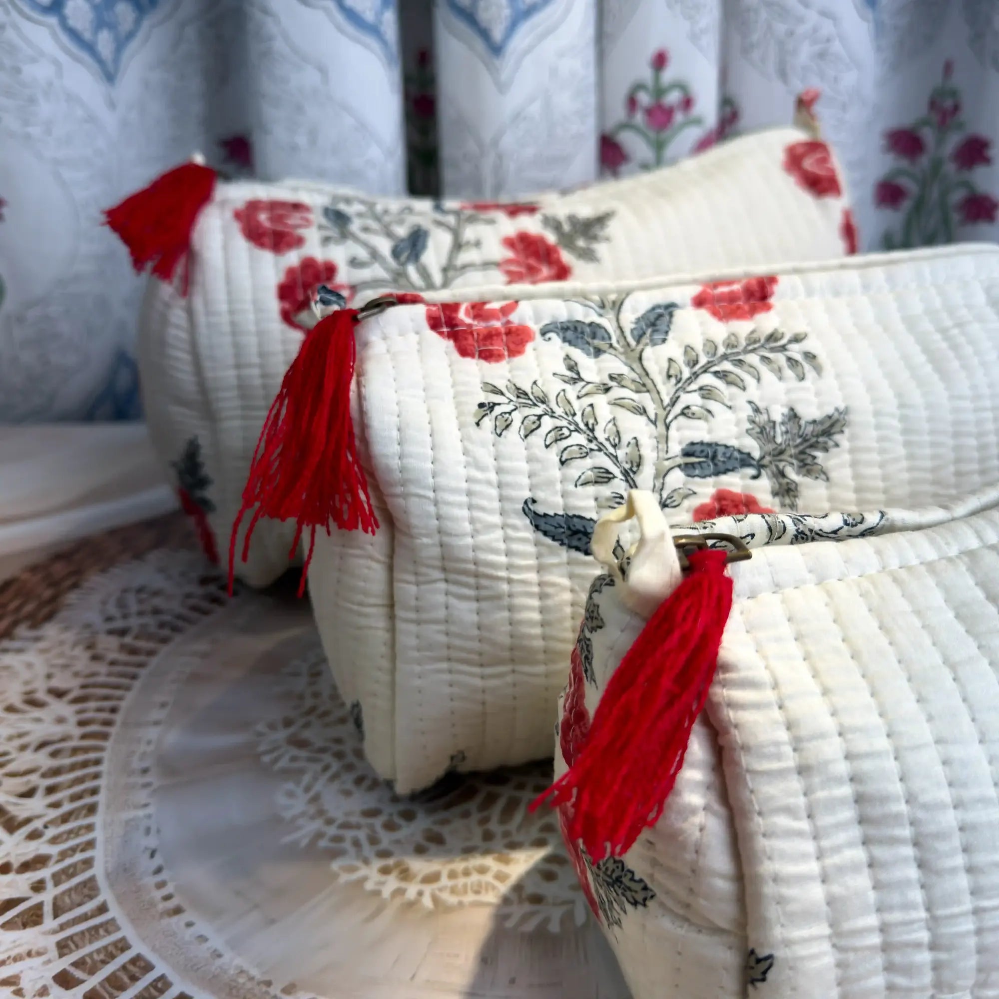 White quilted cotton toiletry pouch set with red and green botanical floral hand block print, three-piece handcrafted organizer with tassels for travel.