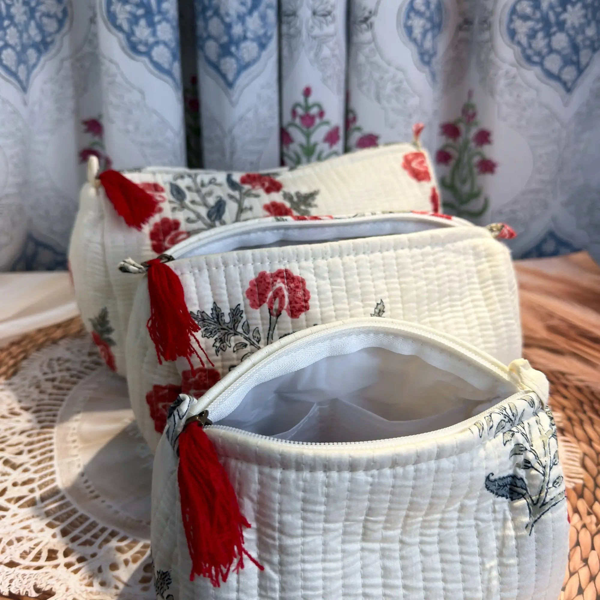 White quilted cotton toiletry pouch set with red and green botanical floral hand block print, three-piece handcrafted organizer with tassels for travel.