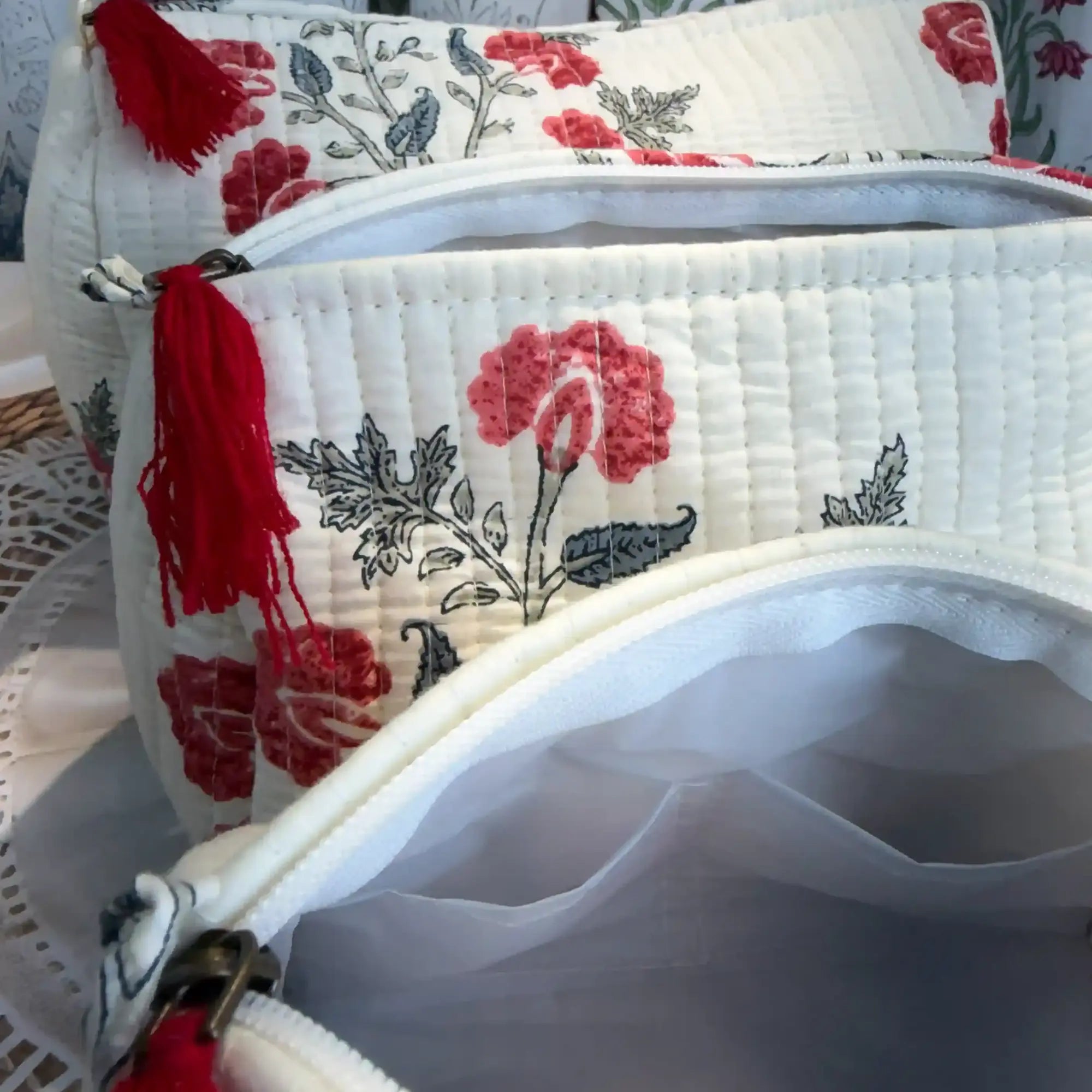 White quilted cotton toiletry pouch set with red and green botanical floral hand block print, three-piece handcrafted organizer with tassels for travel.