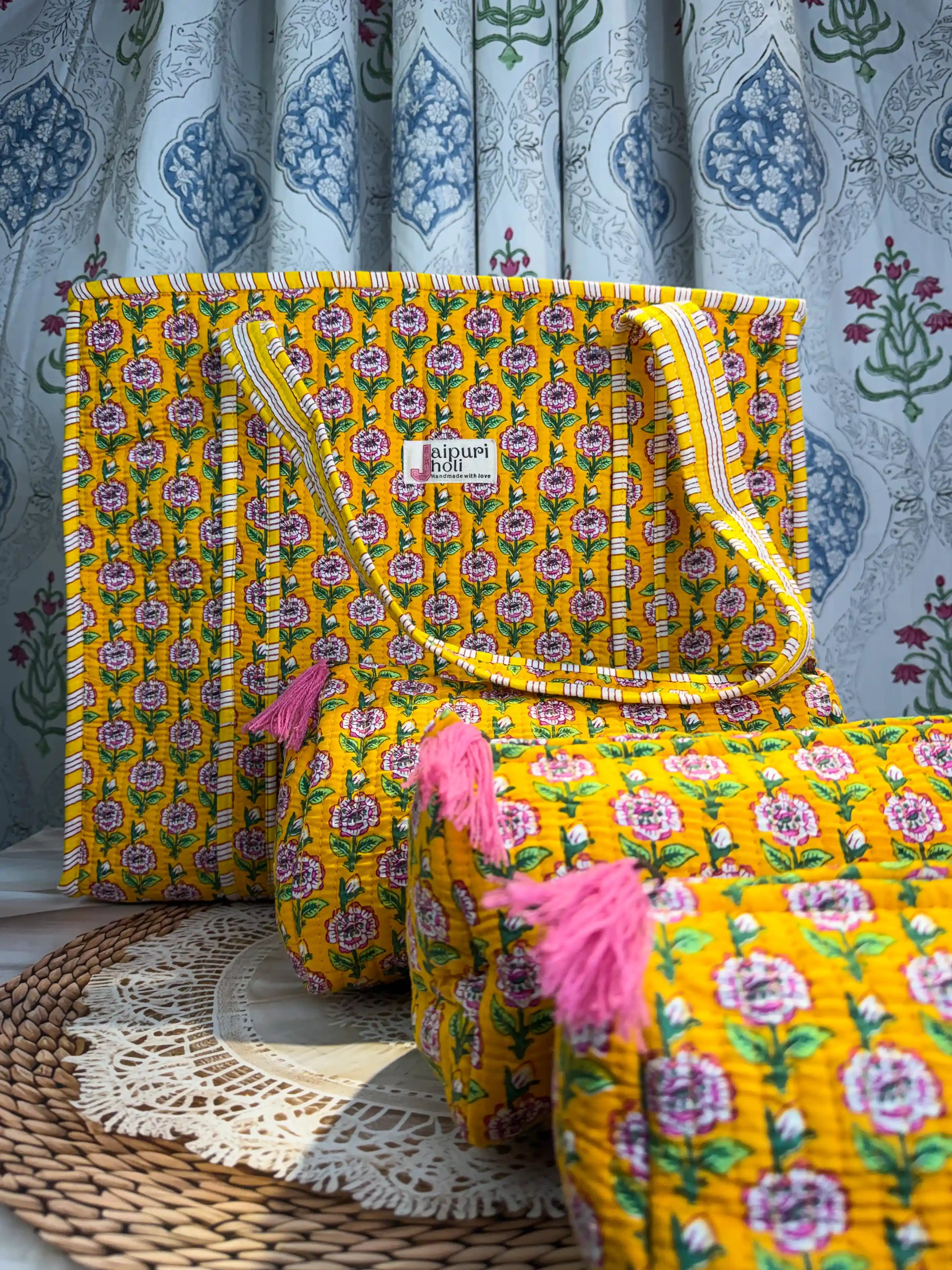 Handcrafted yellow cotton quilted tote bag with floral hand block print and striped handles, paired with a matching 3-piece zippered toiletry pouch set featuring tassel details, ethically made in Jaipur, India, ideal for everyday use, travel, cosmetics, skincare, and innerwear storage