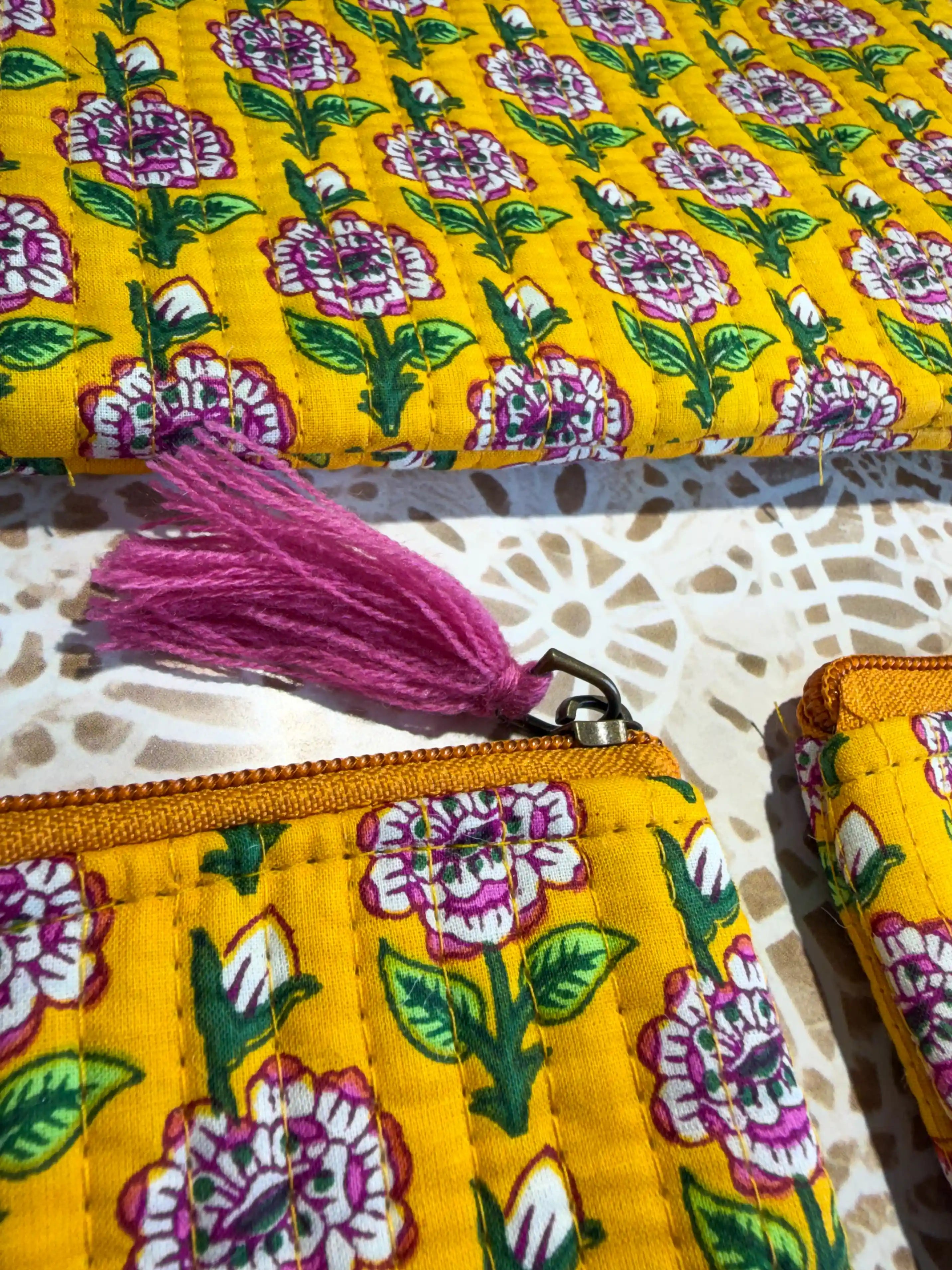 Bright yellow quilted cotton flat pouch set with multicolor floral hand block design, three-piece lightweight handcrafted zipper organizer for daily essentials.