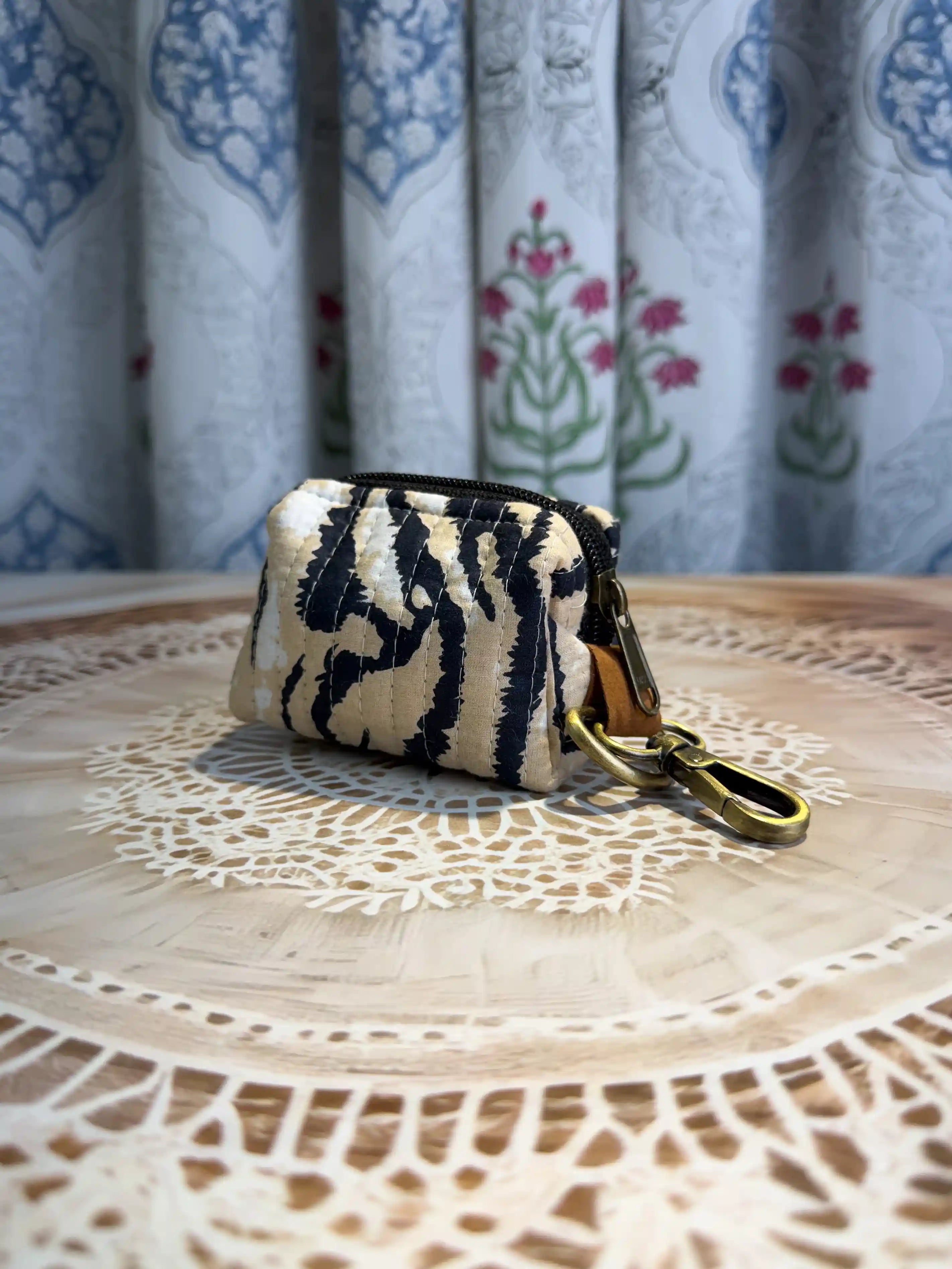 Trending animal print quilted cotton mini pouch with black animal stripes on white background, hand block printed with zipper closure and brass keyring attachment.