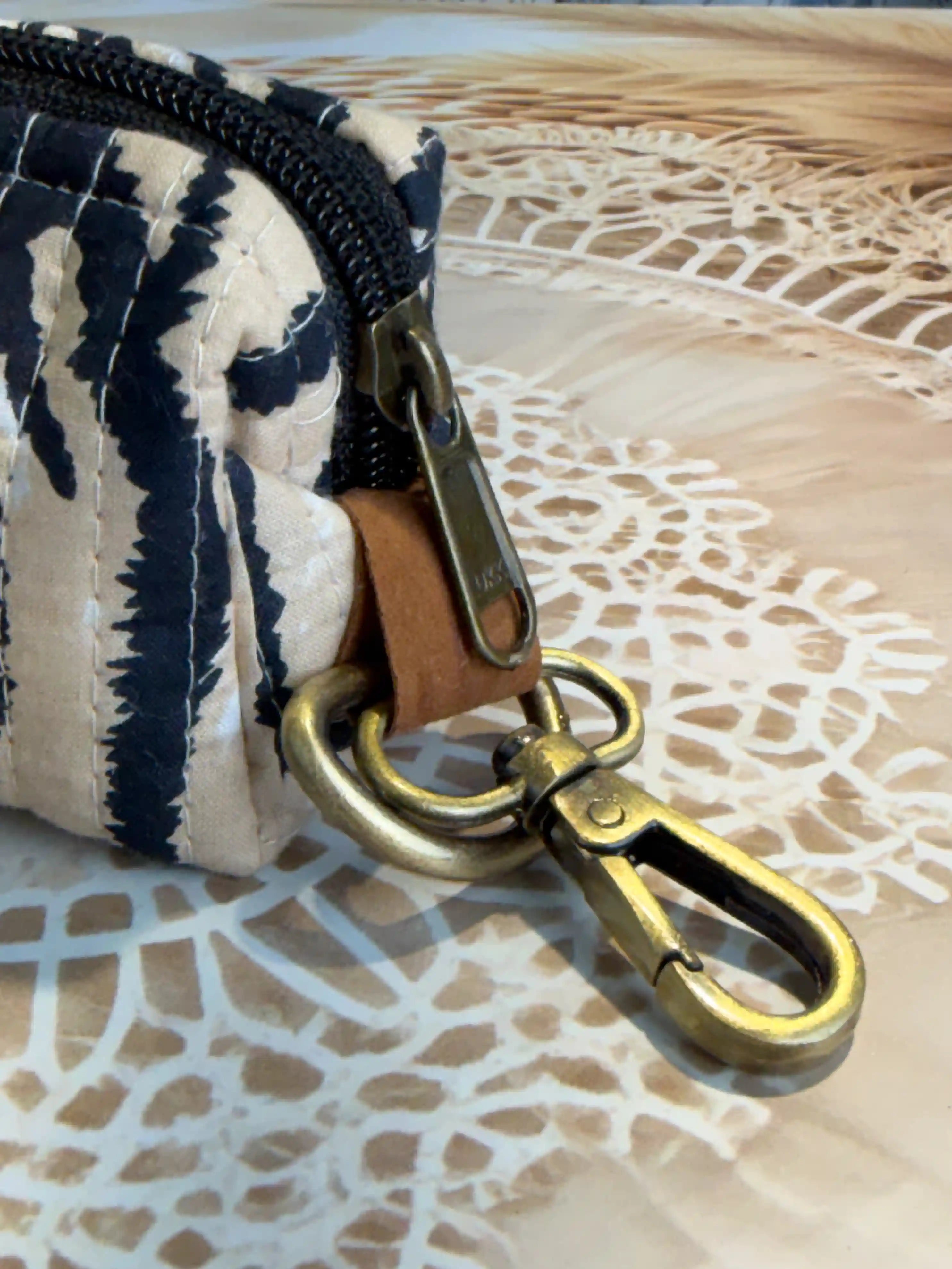 Trending tiger print quilted cotton mini pouch with black tiger stripes on cream background, hand block printed with zipper closure and brass keyring attachment.