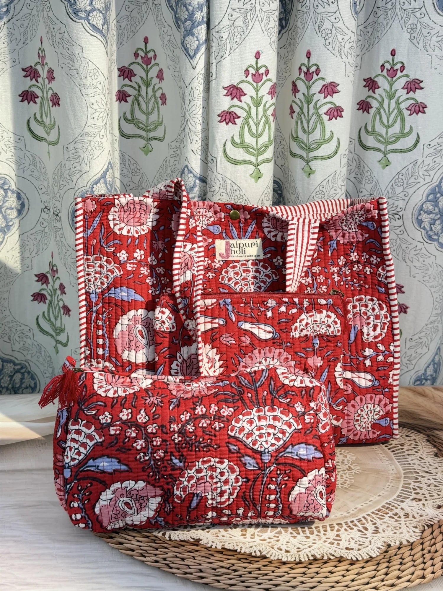 Jaipur block print medium cotton quilted reversible tote bag with matching toiletry pouch and flat pouch, red floral print, 15 × 12 × 6 inch tote with button closure, 10 × 6 inch toiletry pouch and 9 × 7 inch flat pouch front view