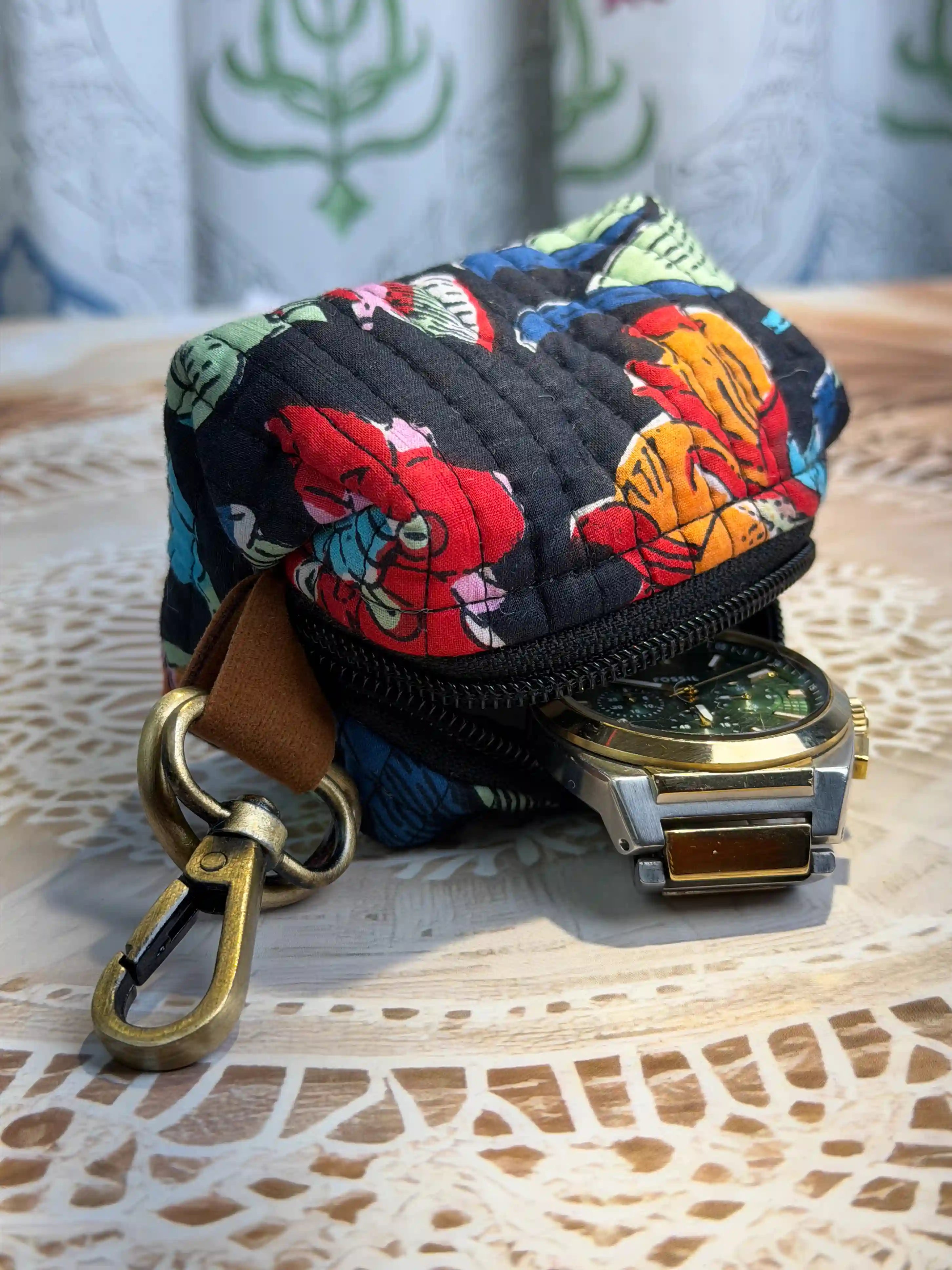 Hand block printed quilted cotton keychain pouch with multicolor floral design on black background, featuring red, yellow, and blue flowers with zip closure and metal keyring for coins and keys.