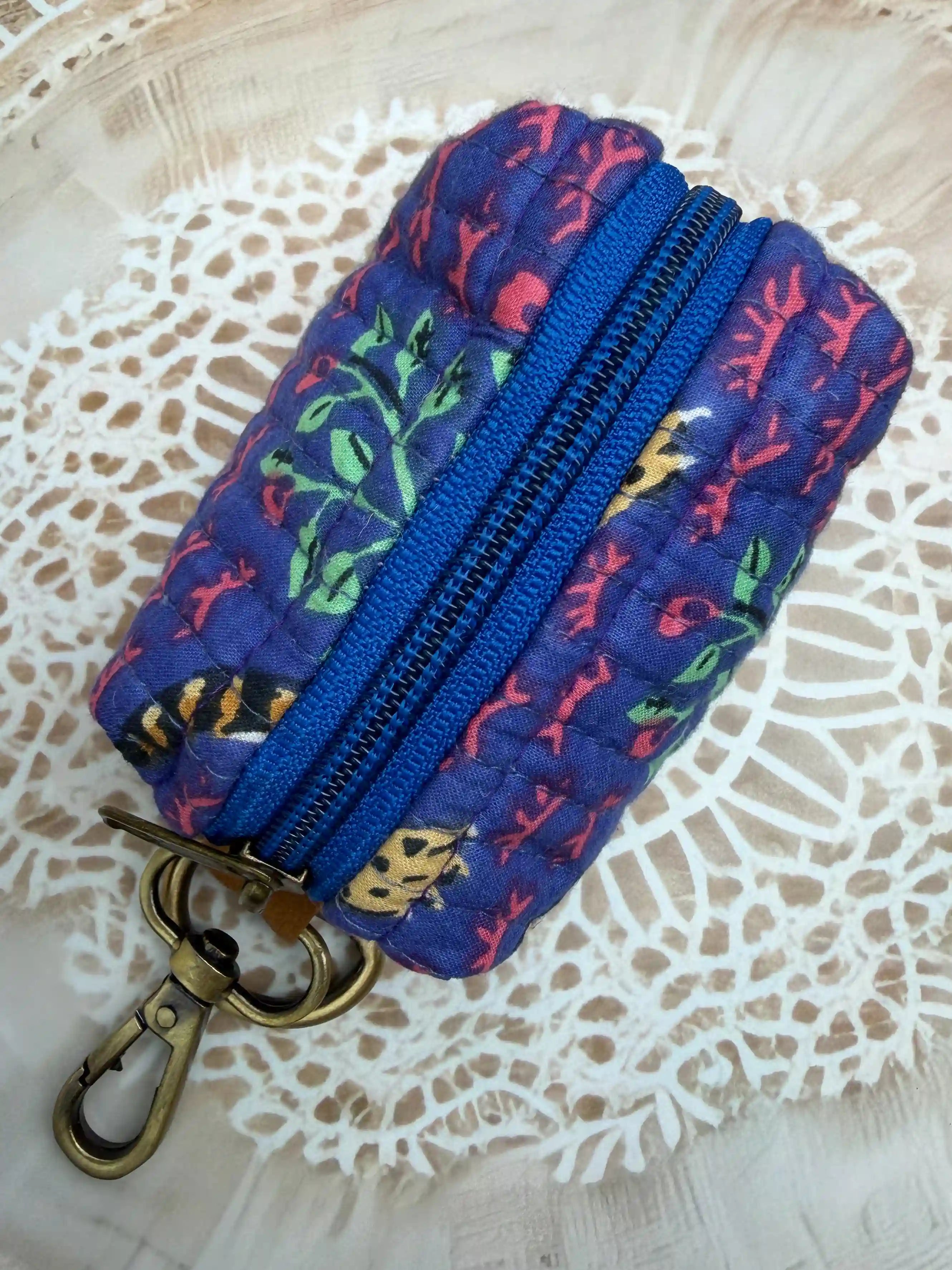 Blue quilted cotton keychain pouch with red floral jaipuri handblock print, zip closure and metal keyring for daily key storage.

