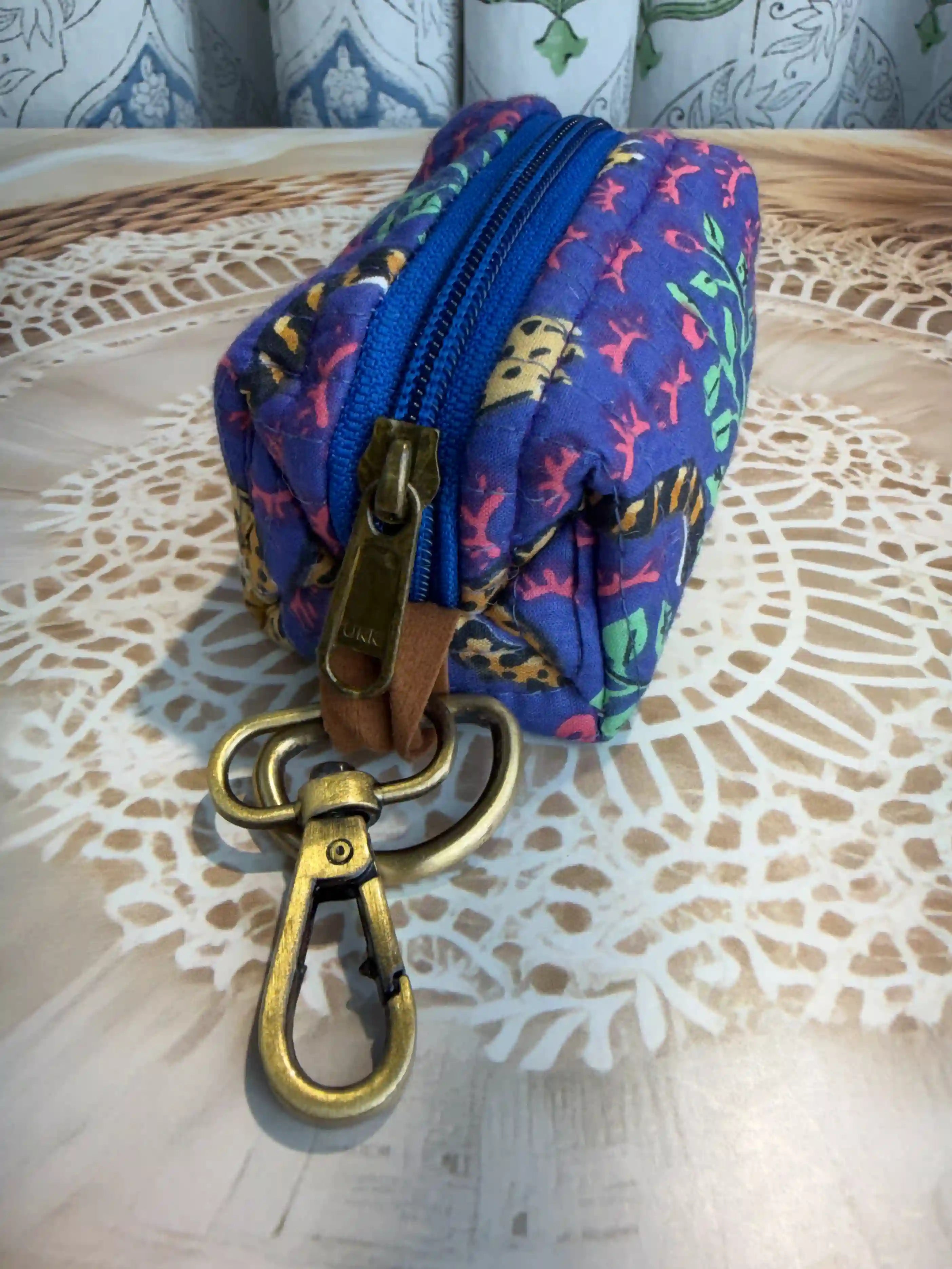 Blue quilted cotton keychain pouch with red floral jaipuri handblock print, zip closure and metal keyring for daily key storage.