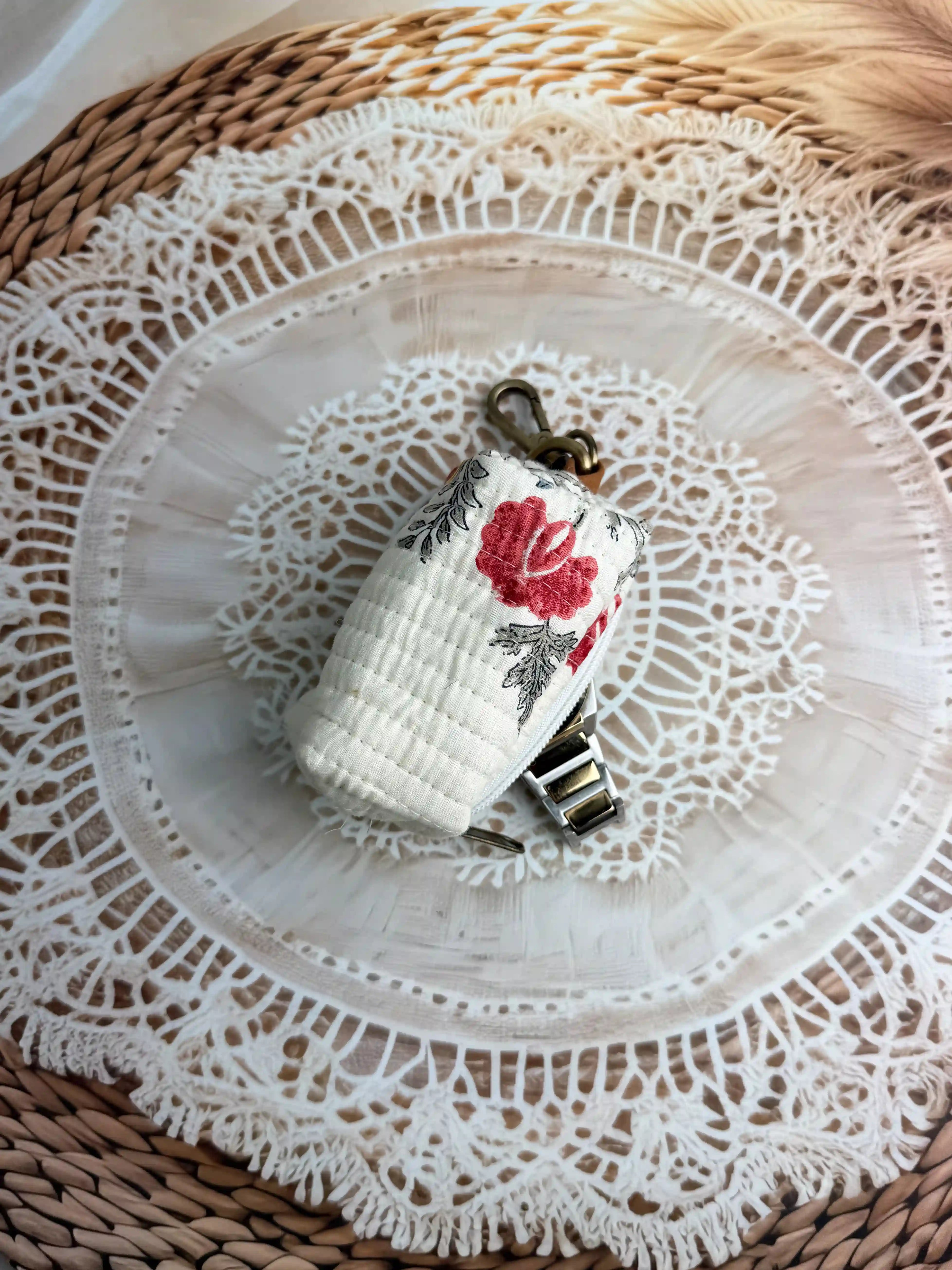 Cream quilted cotton keychain pouch with hand block printed red floral botanical design, zip closure with metal keyring for carrying small essentials and cosmetics.
