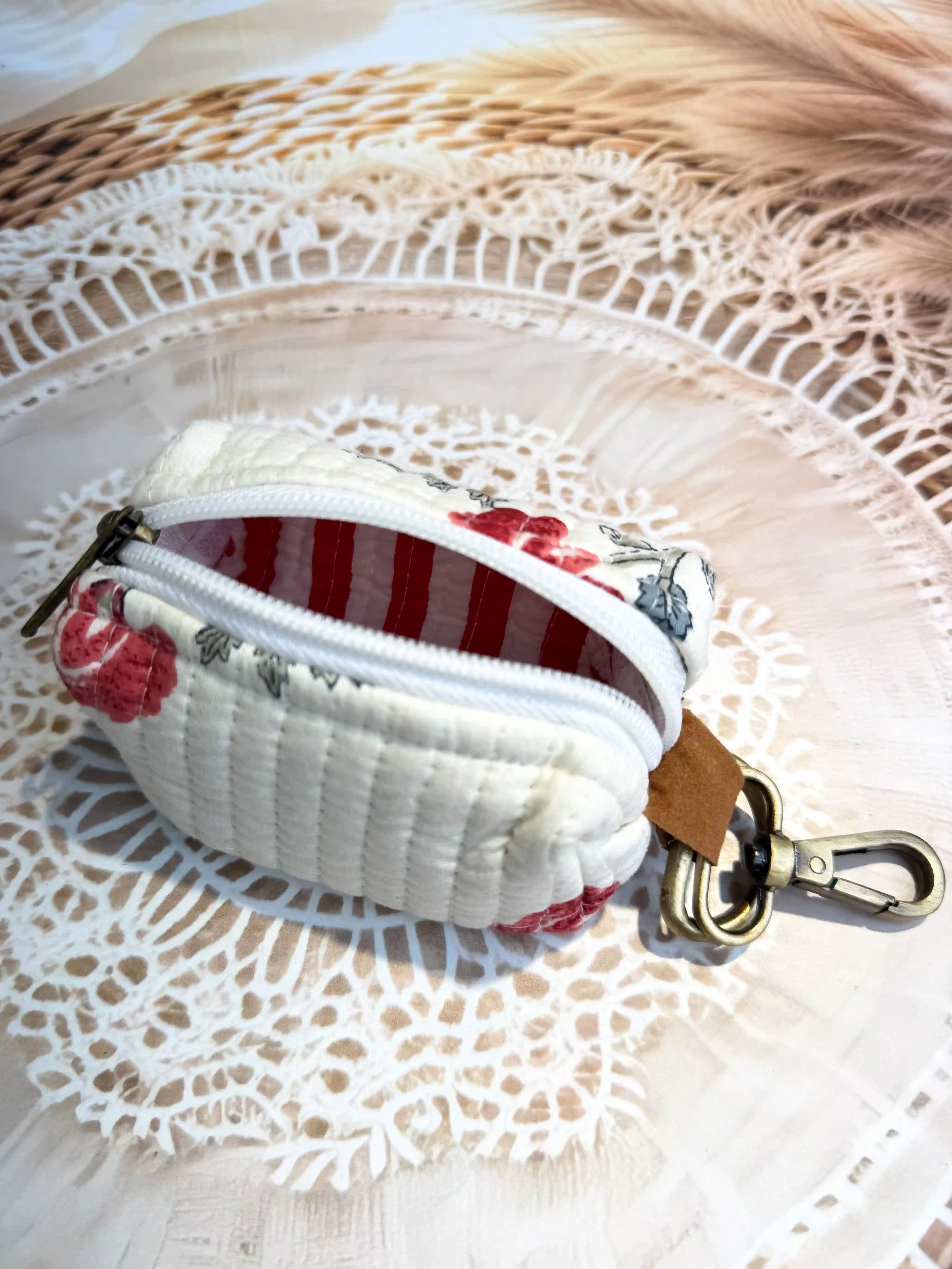 Cream quilted cotton keychain pouch with hand block printed red floral botanical design, zip closure with metal keyring for carrying small essentials and cosmetics.