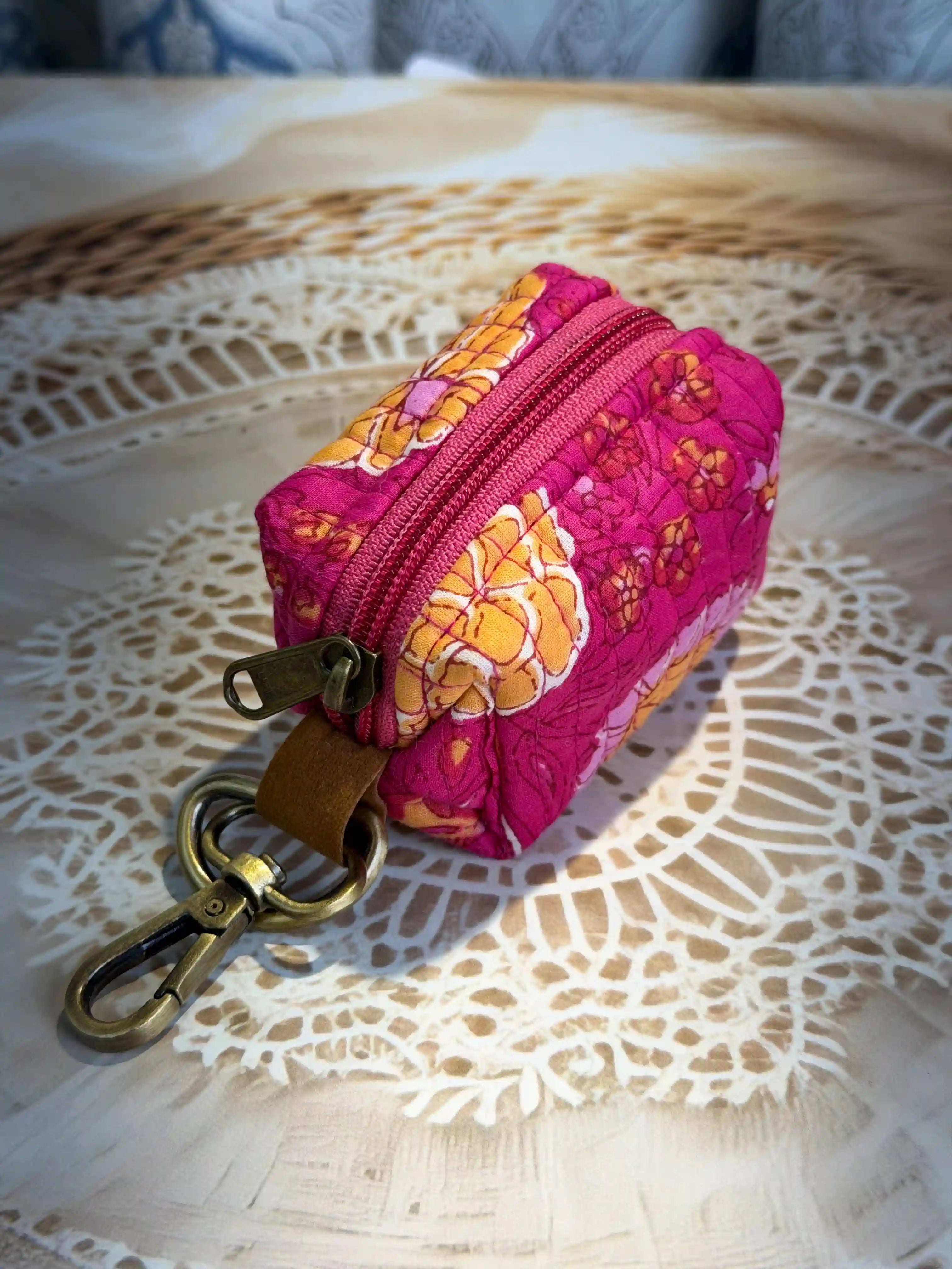 Pink quilted cotton keychain pouch with jaipuri handblock floral print, zip closure and metal keyring for organizing small items.
