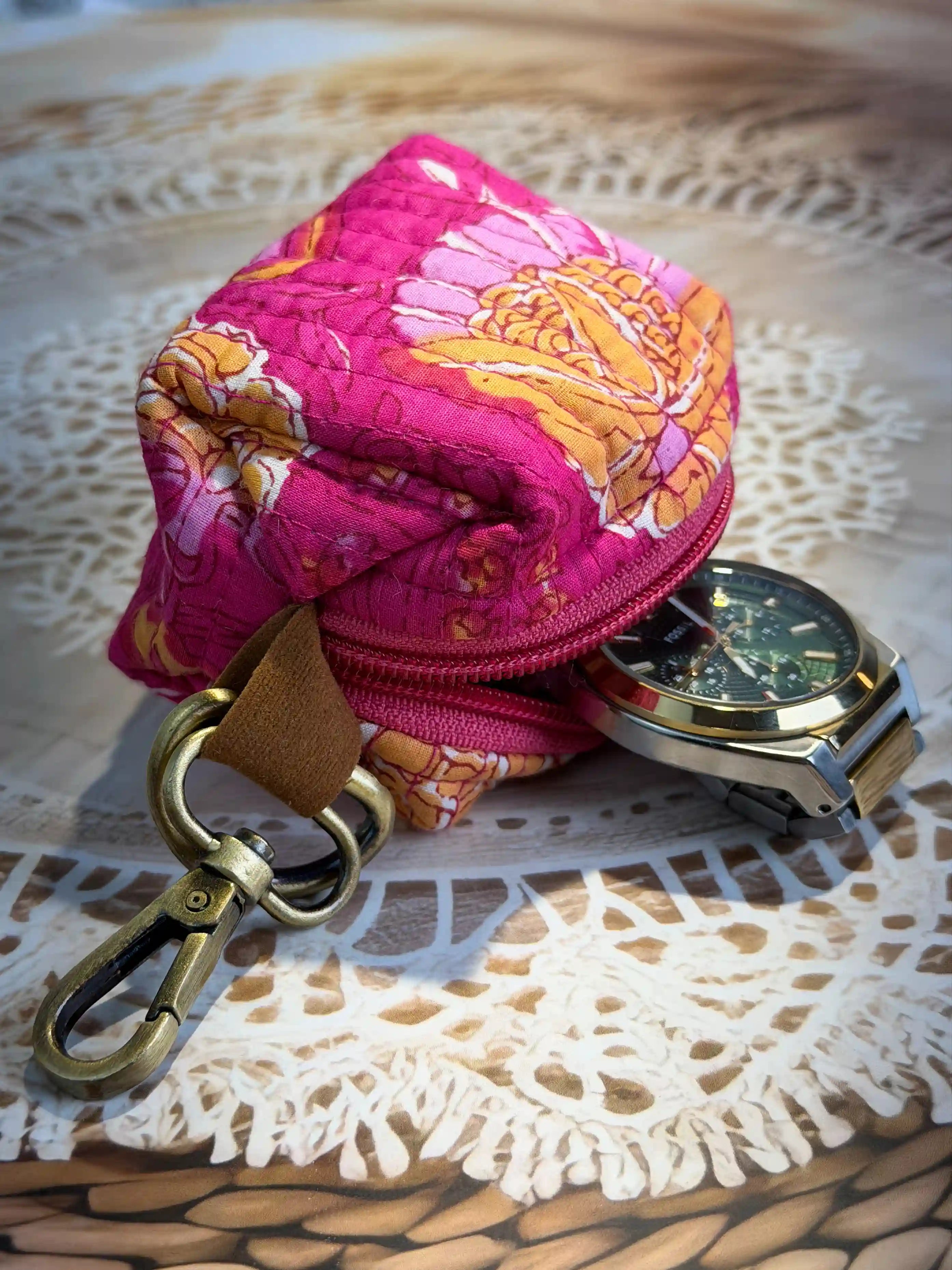 Pink quilted cotton keychain pouch with hand block floral print in gold and traditional design, durable zipper closure with brass keyring for organizing small items.
