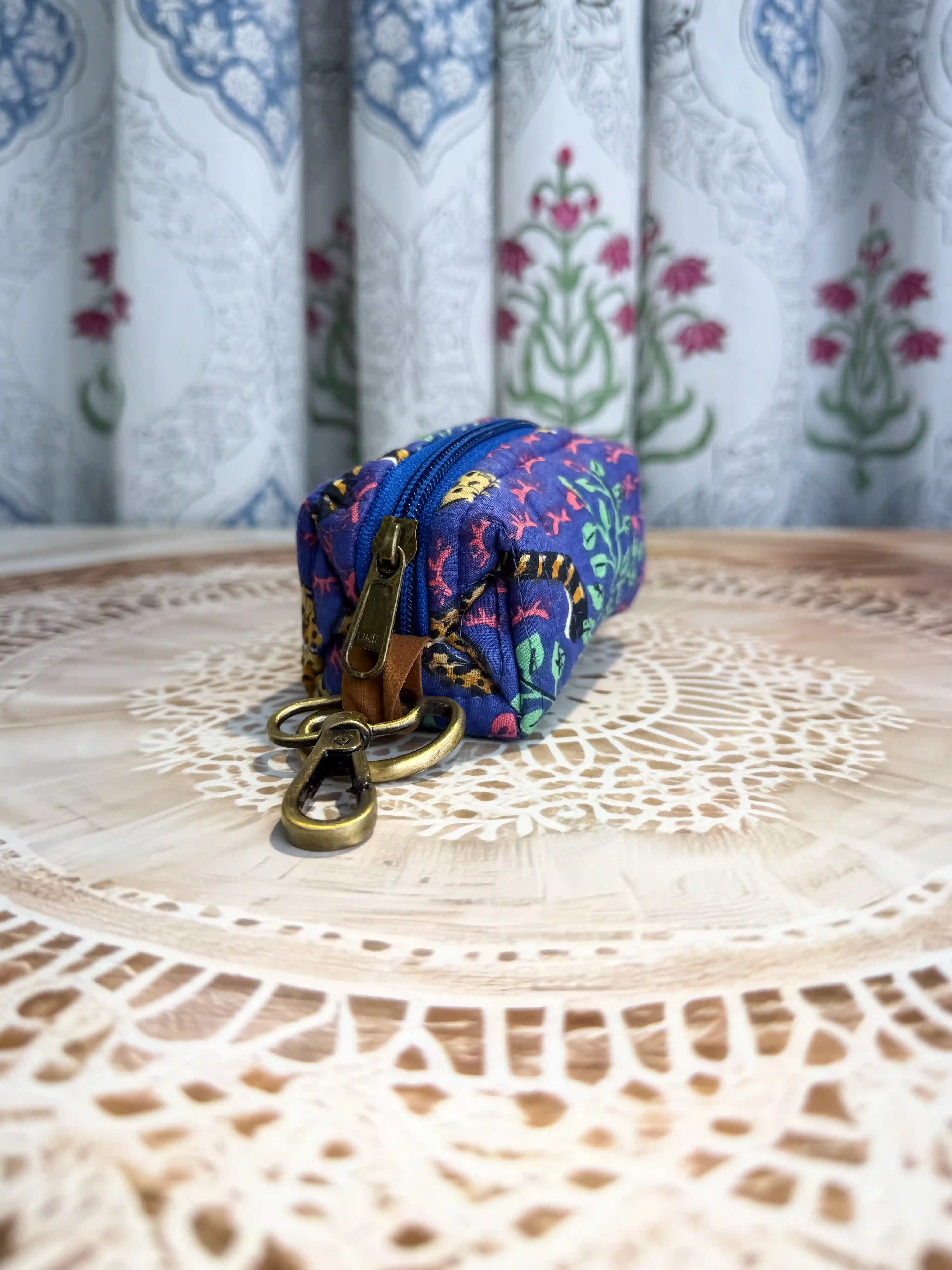Blue quilted cotton keychain pouch with hand block printed red flowers and green leaves design, includes zip closure and sturdy metal keyring for daily carry.
