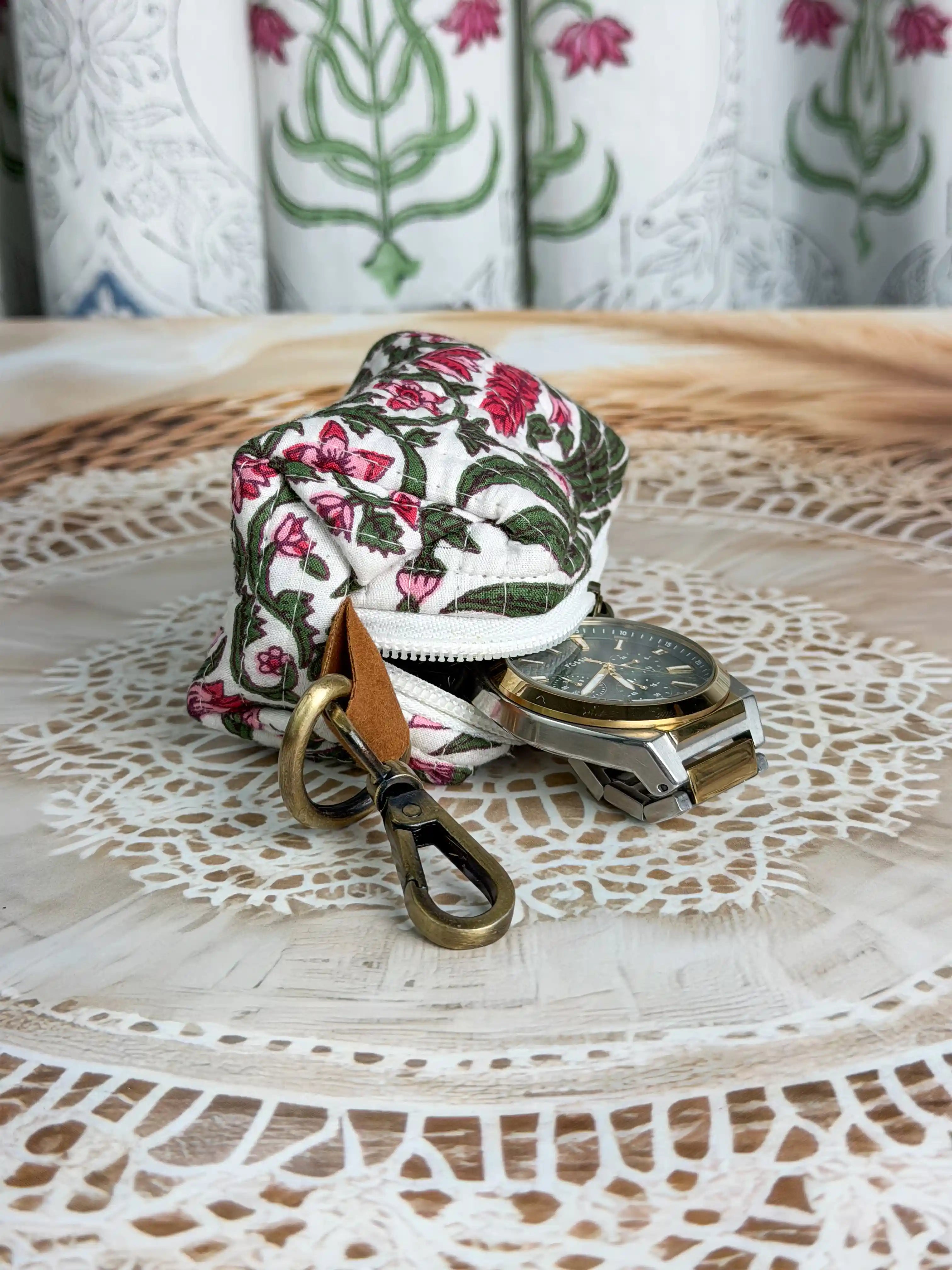 white quilted cotton keychain pouch with hand block printed red and green botanical floral design, durable zipper with metal keyring for carrying coins and essentials.